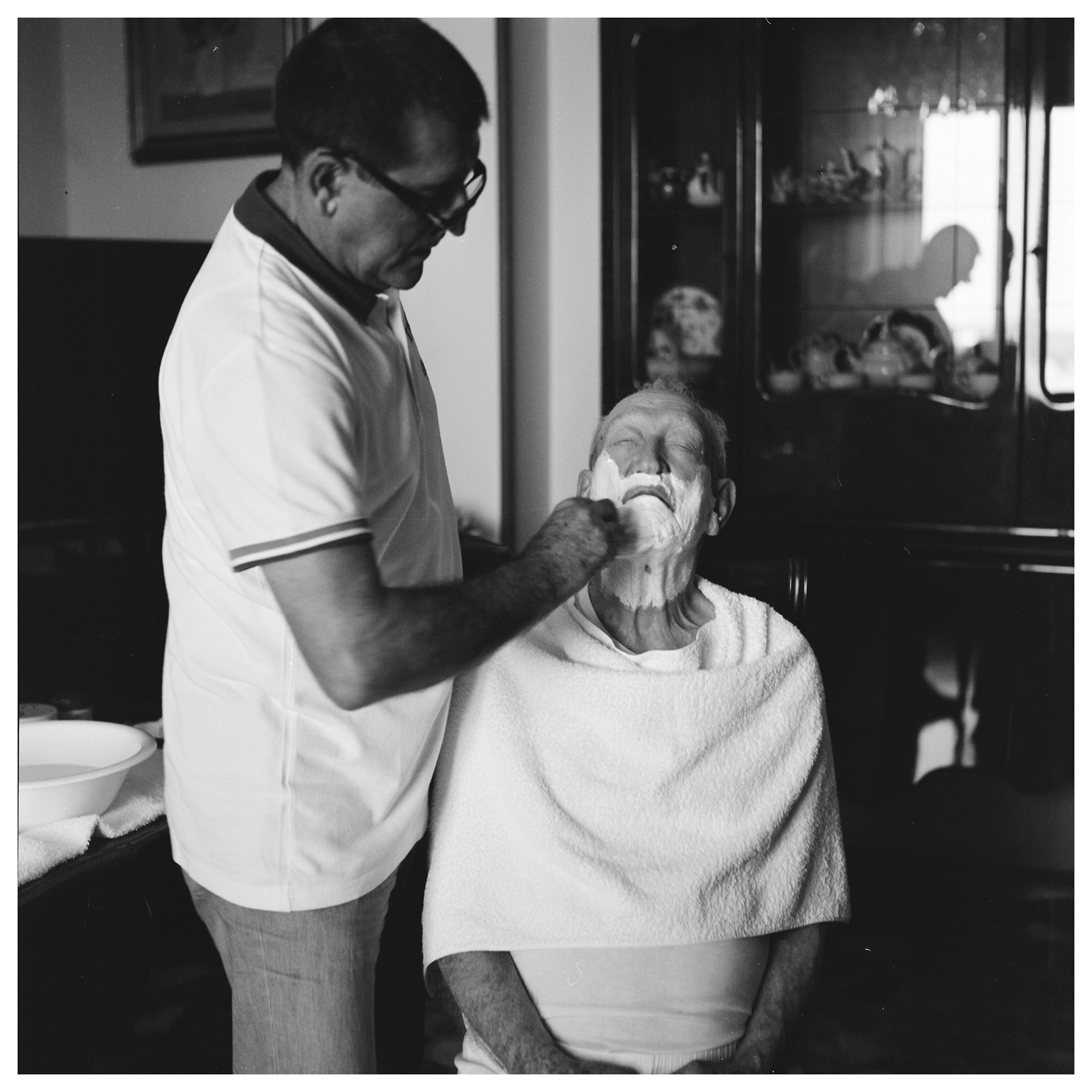 Ritratto in bianco e nero in luce naturale di un uomo che sta rasando la barba in casa al padre - progetto autoriale Andrea Palumbo fotografo