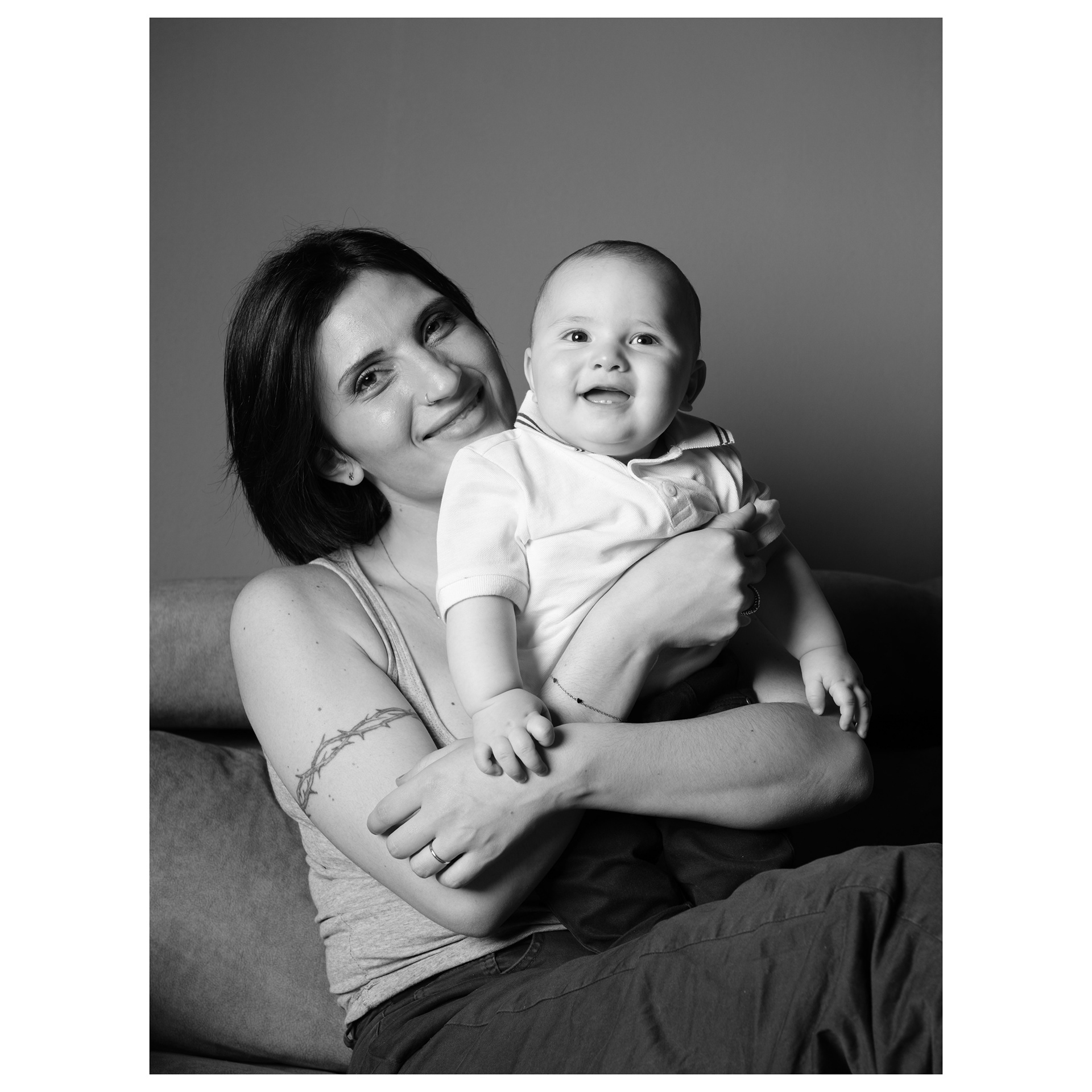 ritratto fotografico in bianco e nero di una mamma sorridente con suo figlio molto piccolo in braccio - Andrea Palumbo fotografo