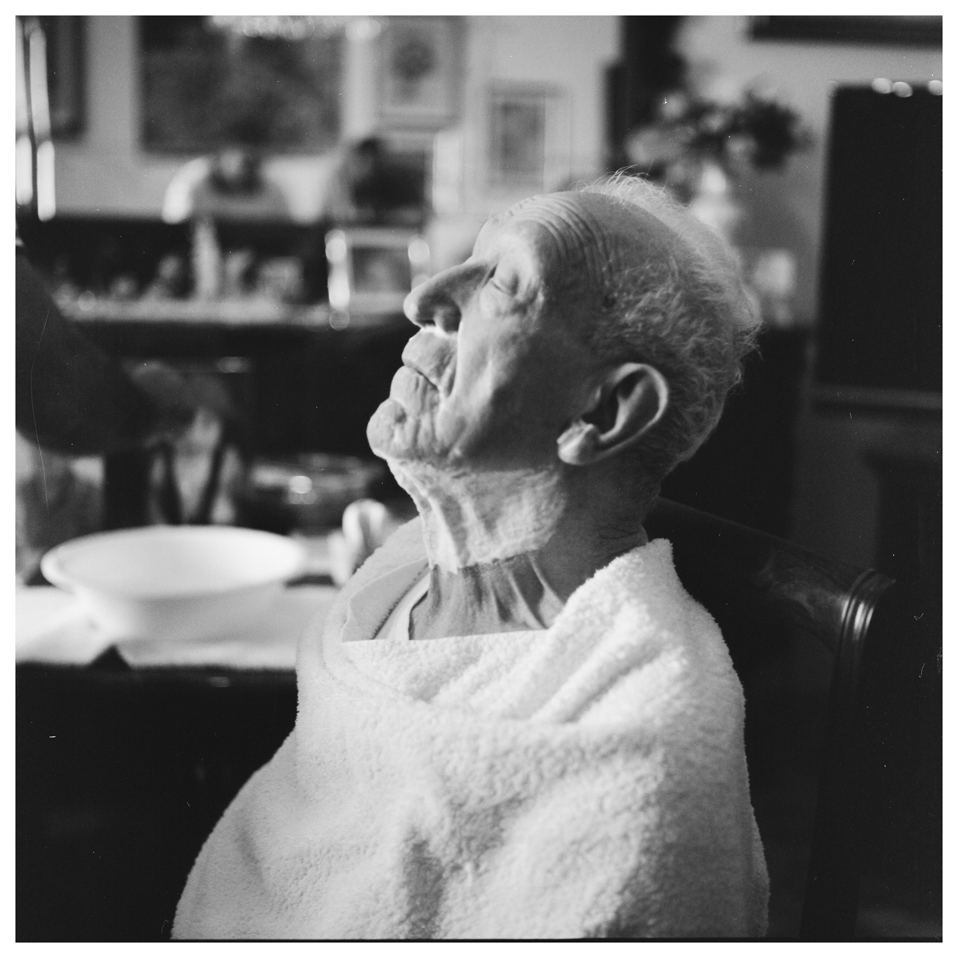 Ritratto fotografico in bianco e nero di un anziano di profilo che si sta facendo radere la barba in casa - progetto autoriale Andrea Palumbo fotografo