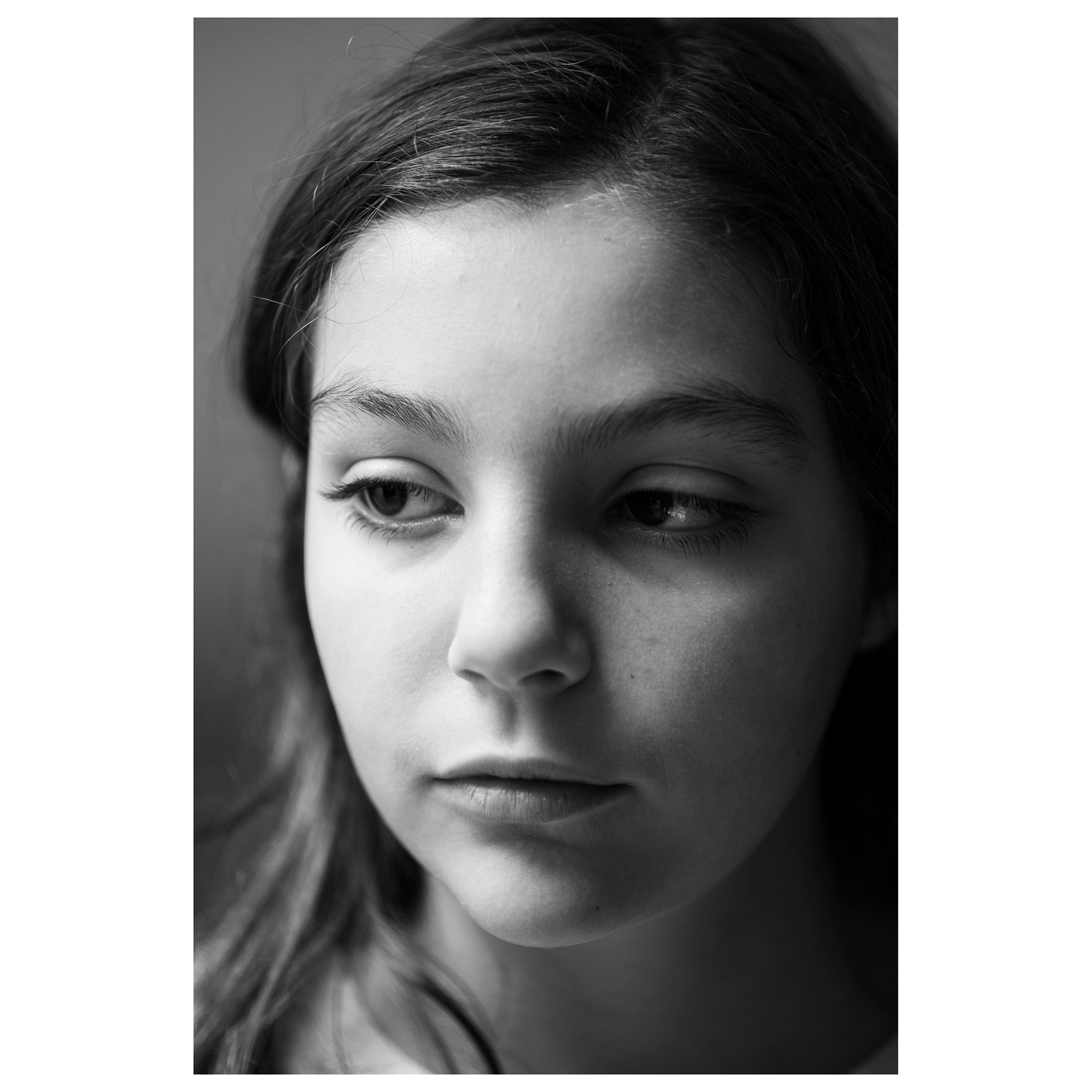 Ritratto in primo piano in bianco enero di una ragazzina che guarda alla sua destra verso la luce che le illumina il viso 