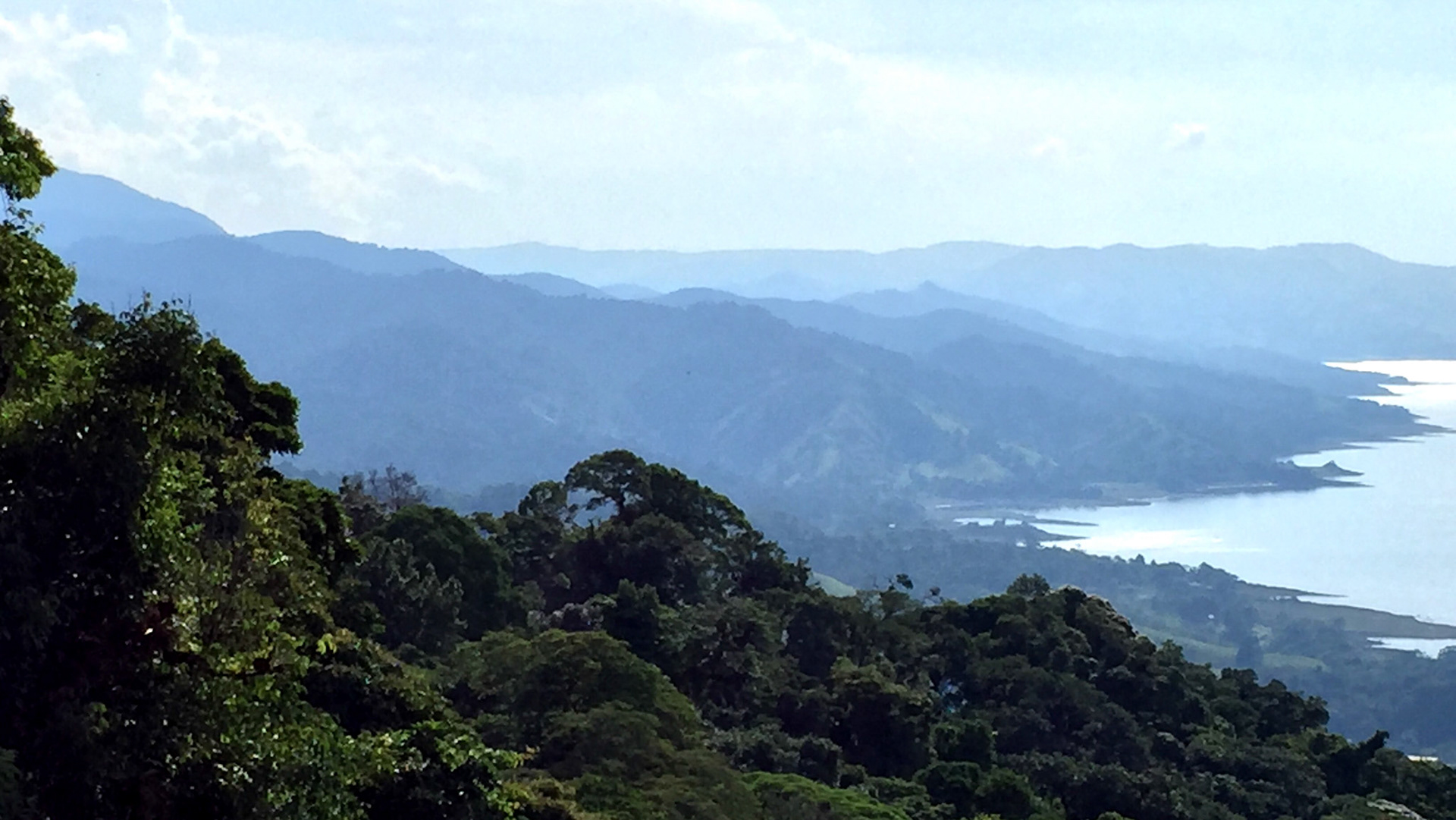 Into the Highlands | The jagged, narrow path into Costa Rica's rugged highlands straddling the Continental Divide is steep and twisted. Progress is slow through thick humidity and deep shades of Equatorial green. This view shows how quickly the landscape turns vertical at the shores of Arenal de Laguna as you head into the mountains.