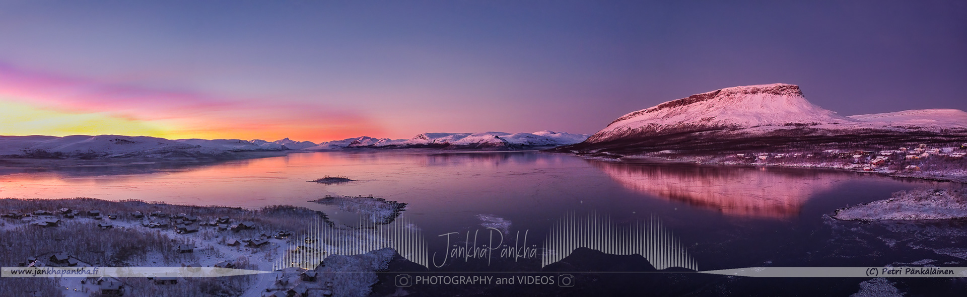 Mirror-like ice on Lake Kilpisjärvi capturing the pastel shades of a winter sunset in Enontekiö