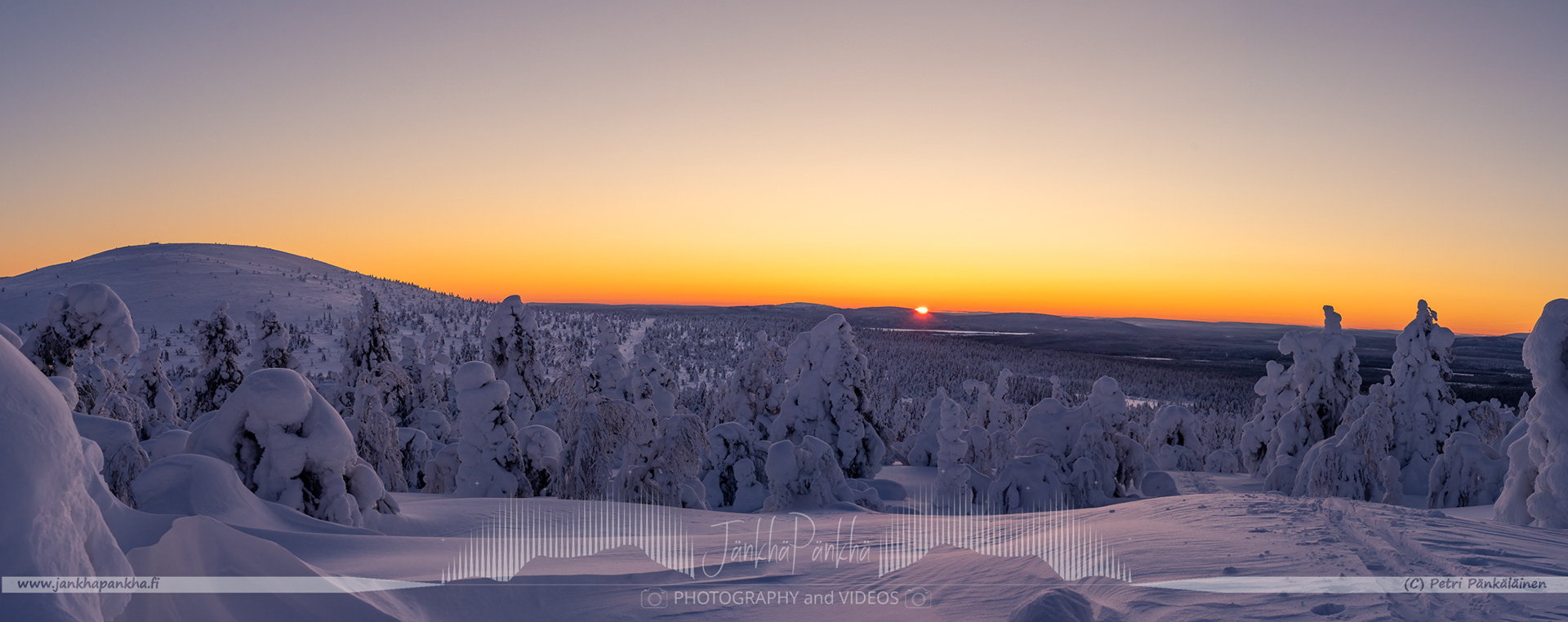 Vibrant orange and yellow hues painting the sky during a polar night in Lapland's Pallas-Yllästunturi National Park.