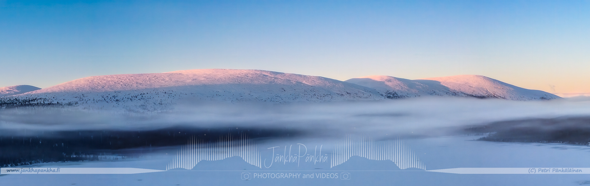 Pallas-Yllästunturi National Park's snowy landscapes bathed in the warm colors of a winter sunrise.