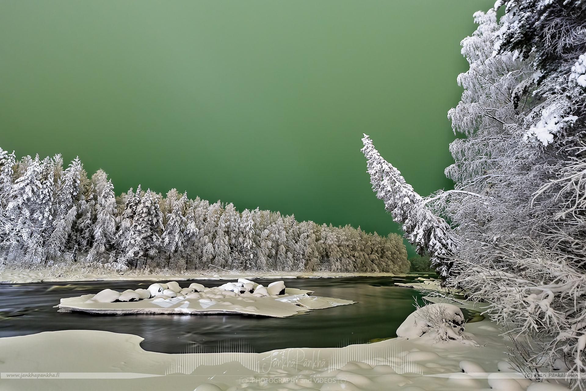Northern lights behind the low hanging clouds painted the whole sky green. White, snowy treens are lightened up by the bright lamp next to the bridge in Vikaköngäs. This is a quite surreal combination of lights I have ever seen..