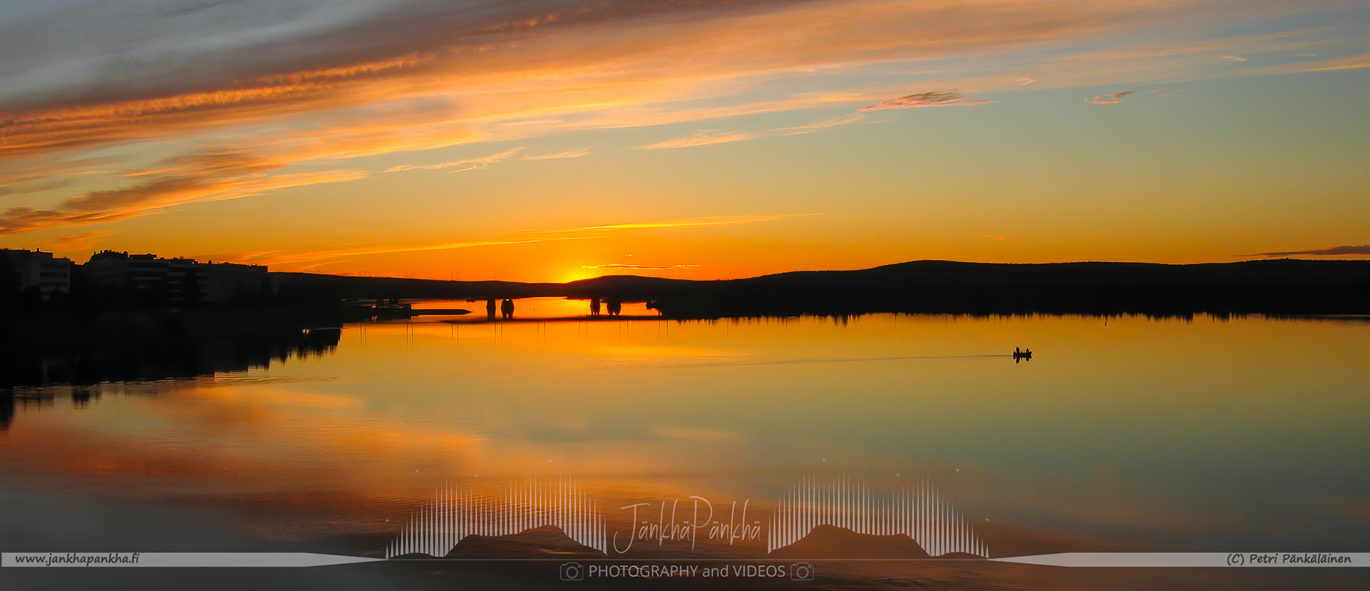 The Ounasjoki bridge at the vibrant sunset and two fishermen rowing a boat.