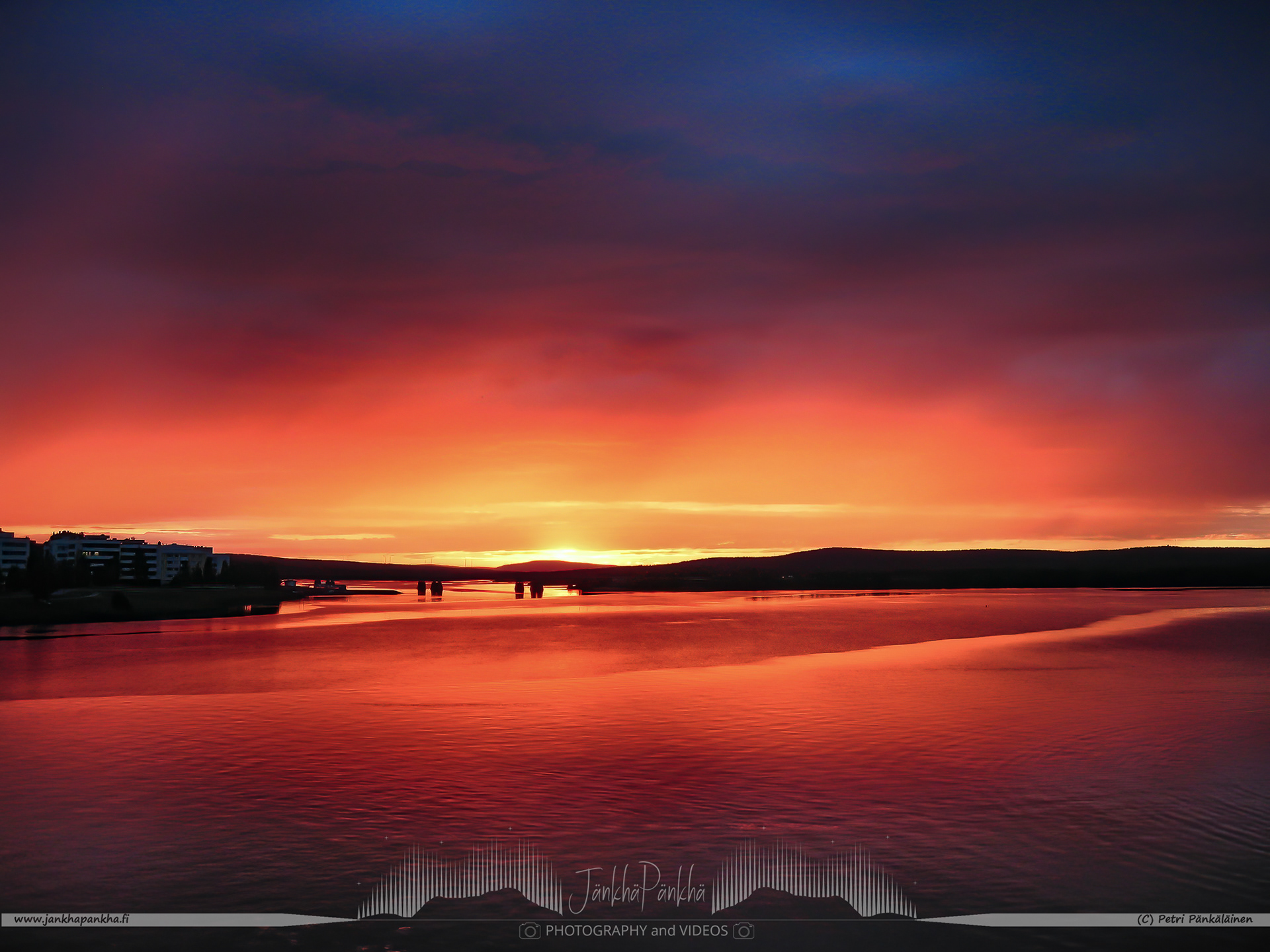 The bridge over the Ounasjoki river at the sunset with exceptionally intense colors of orange, purple and yellow.