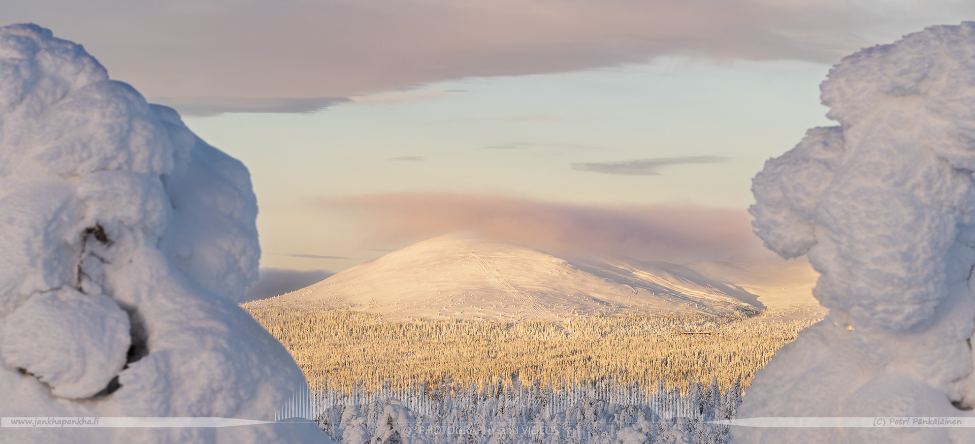 Orange and yellow sunset casting a warm glow over the snowy landscapes of Pallas-Yllästunturi National Park.
