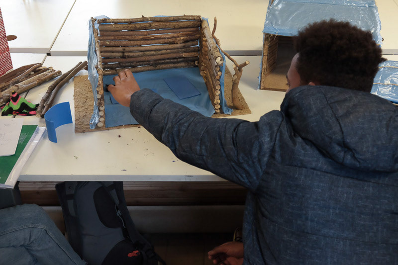 Un migrant commente la maquette du lieu qu'il a décrit