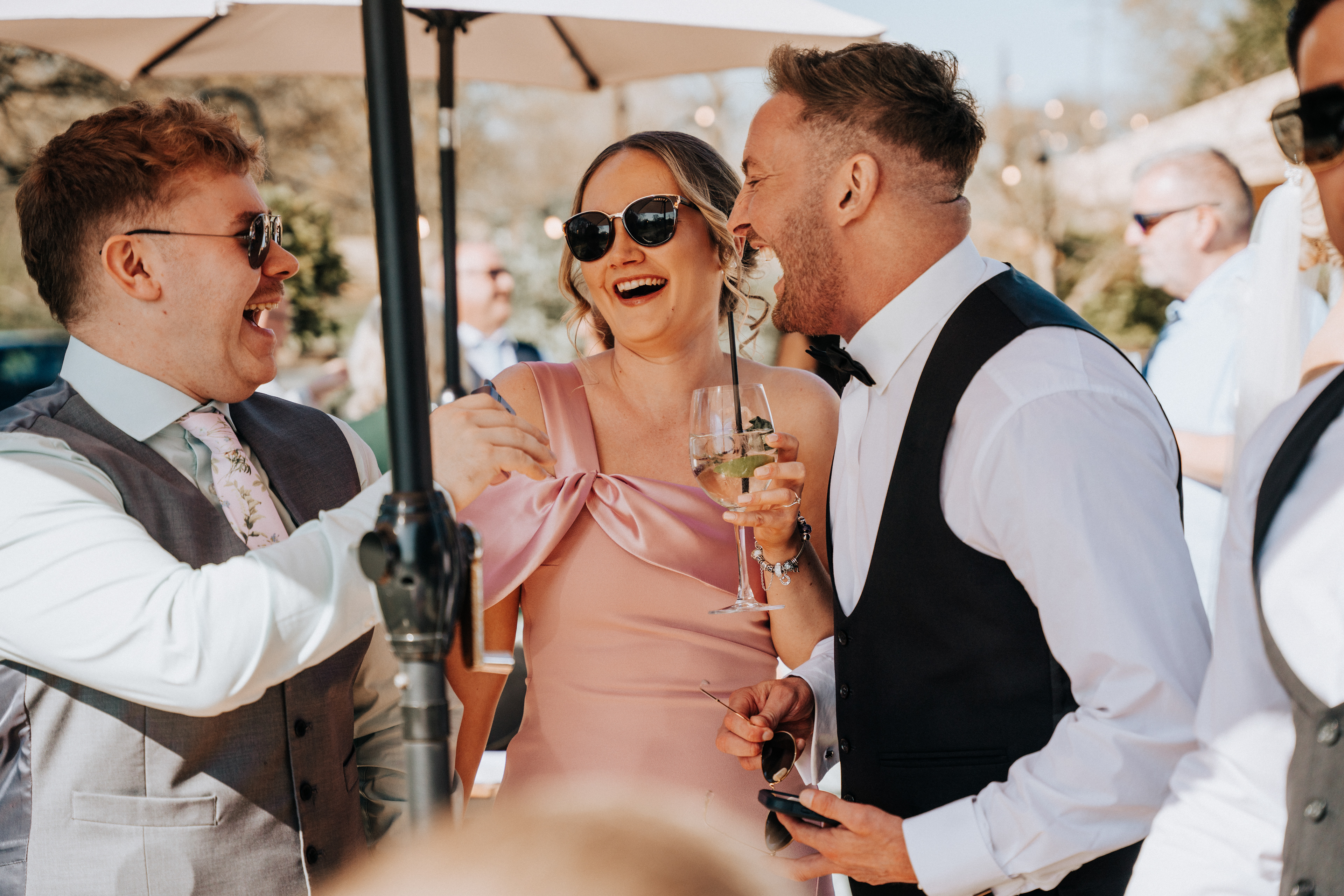 Guests enjoying the outdoor Spring drinks reception at Rivington Hall Barn in Lancashire - candid wedding photography and videography