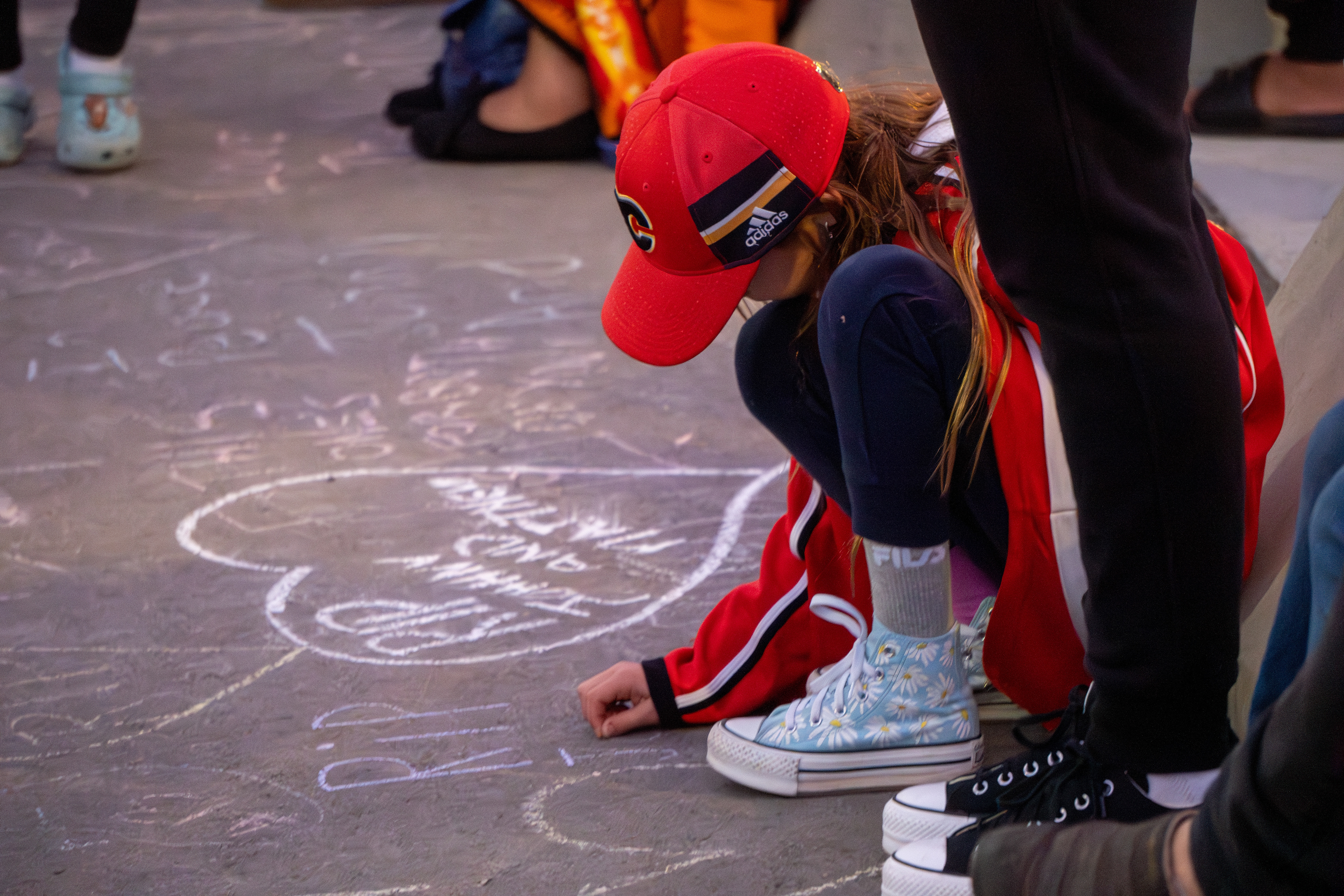 A young fan attending the candlelit vigil adds to the chalk art collection dedicated to Johnny Gaudreau in front of the Saddledome in Calgary on Wednesday, Sept. 4, 2024.