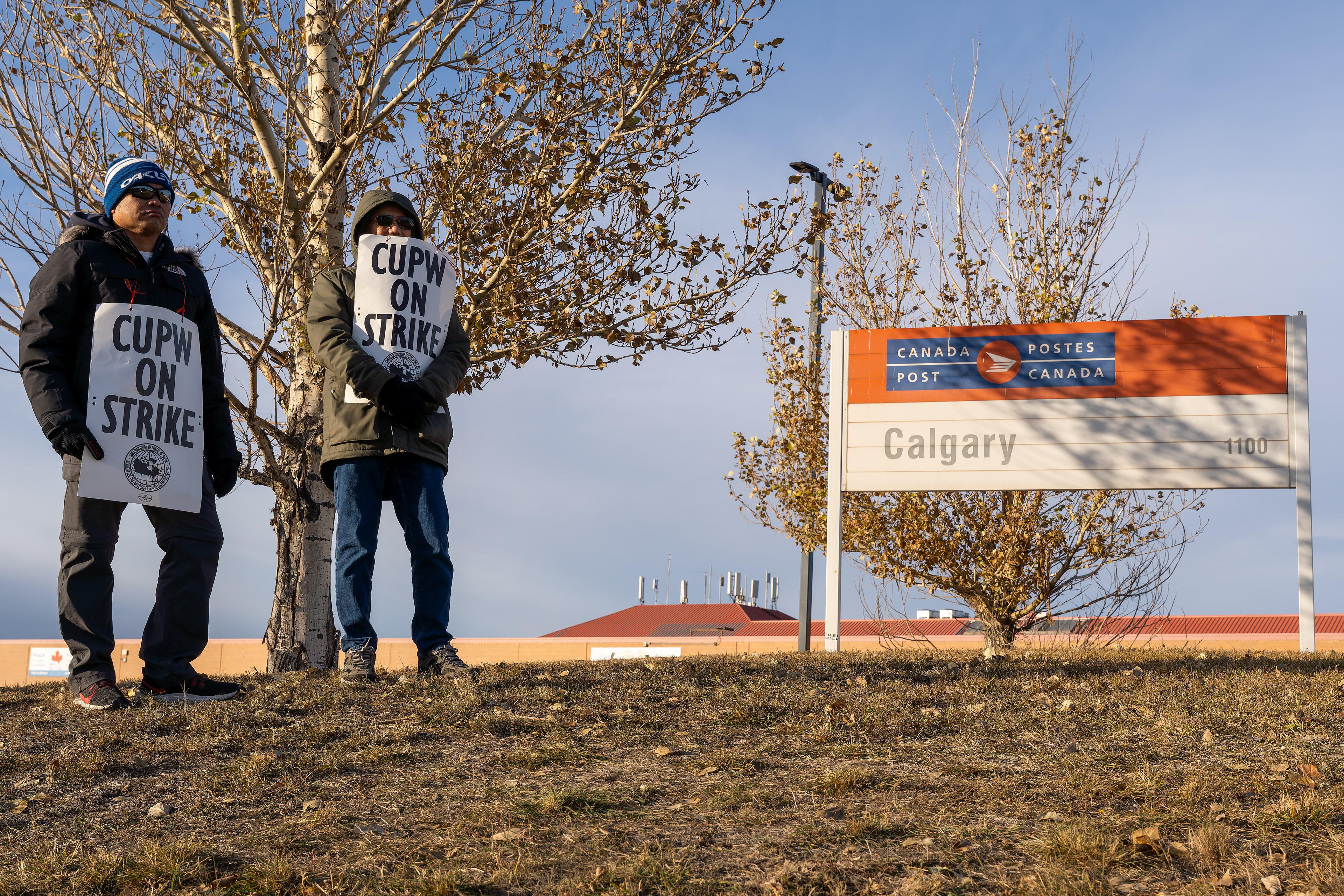Striking employees stand in front of the Canada Post Mail Processing Plant in Calgary on Saturday, Nov. 16, 2024.