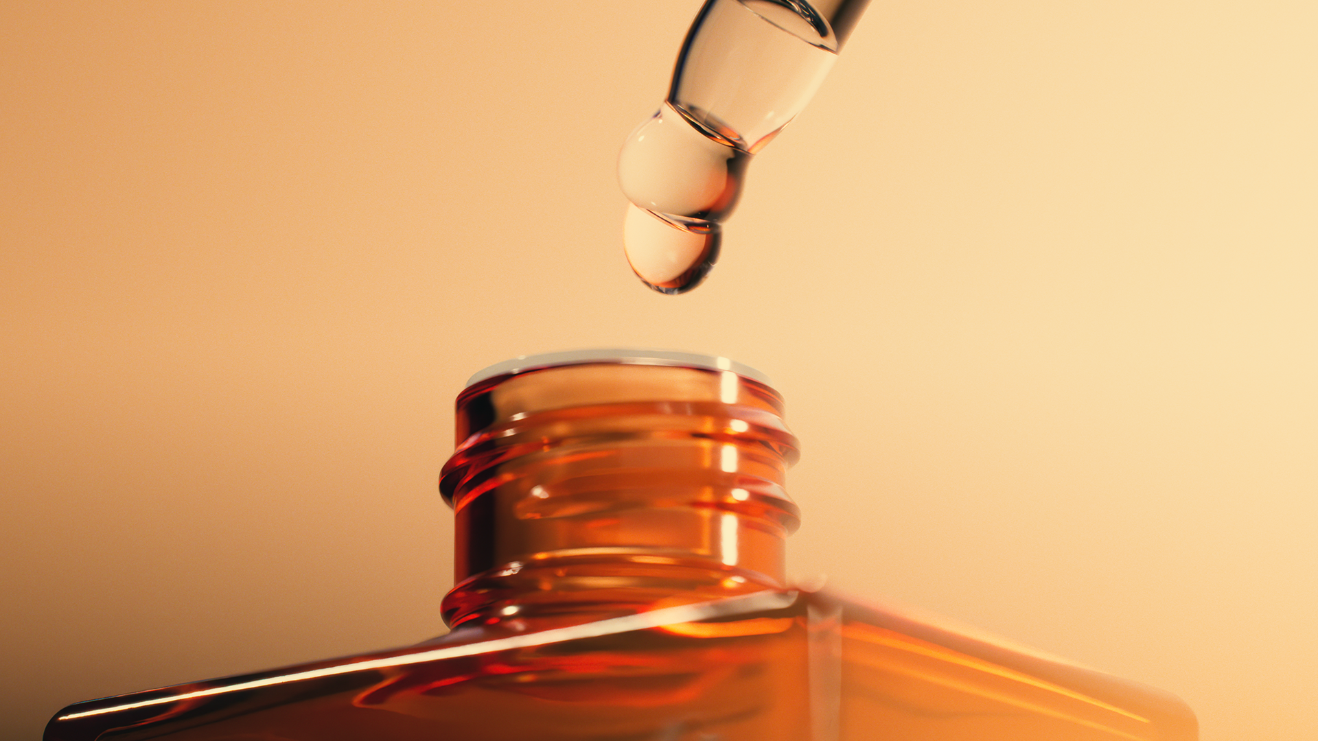A close-up of a dropper dispensing a clear liquid into an amber bottle, showing the precision and care in the process.