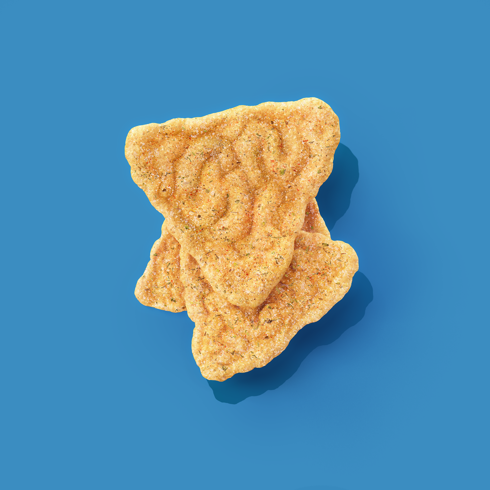 A stack of golden-brown, crispy, seasoned crackers with a crinkled texture on a blue background.