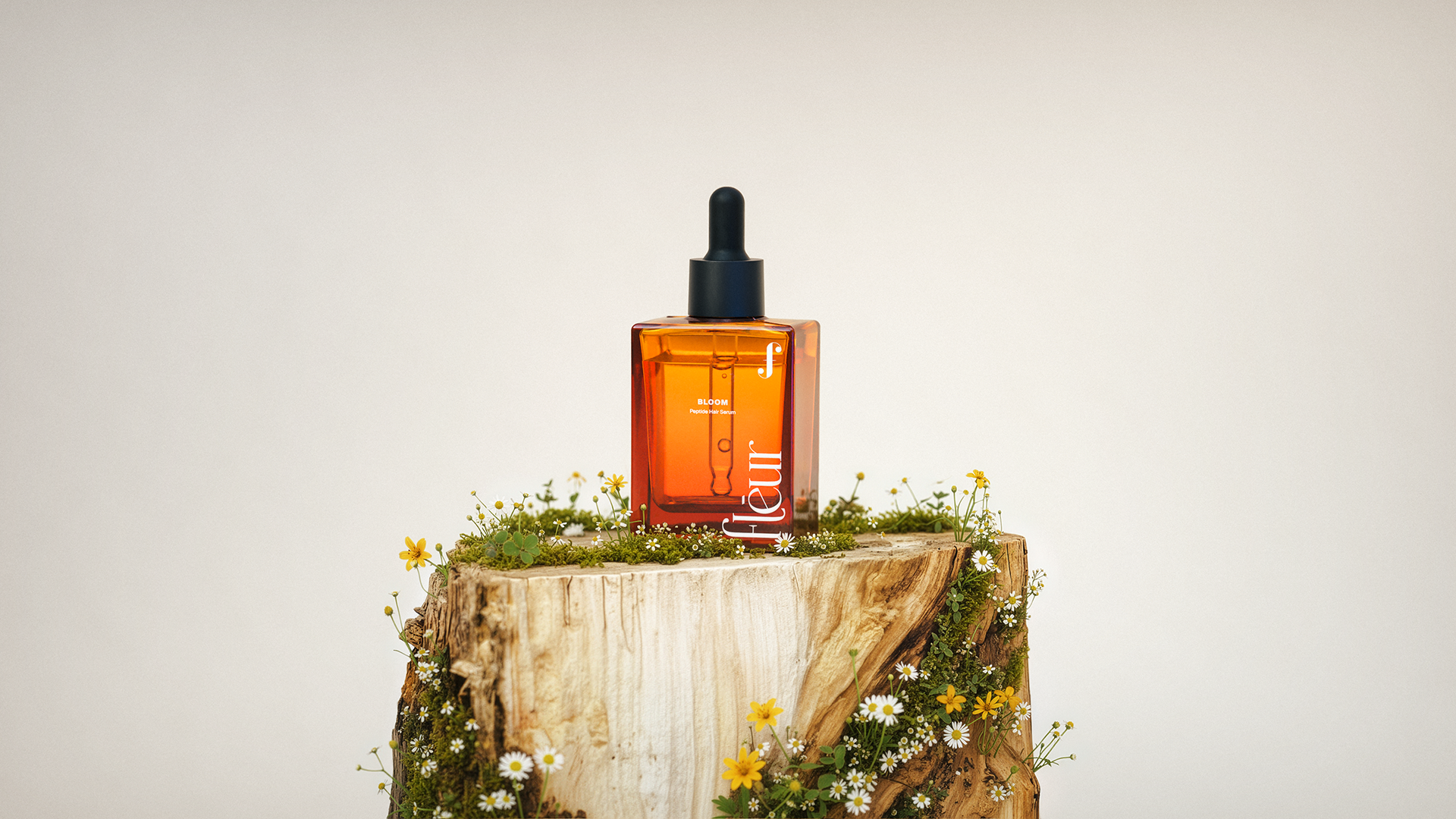 A bottle of "Fleur" serum on a wooden stump surrounded by wildflowers, with the product name prominently displayed.