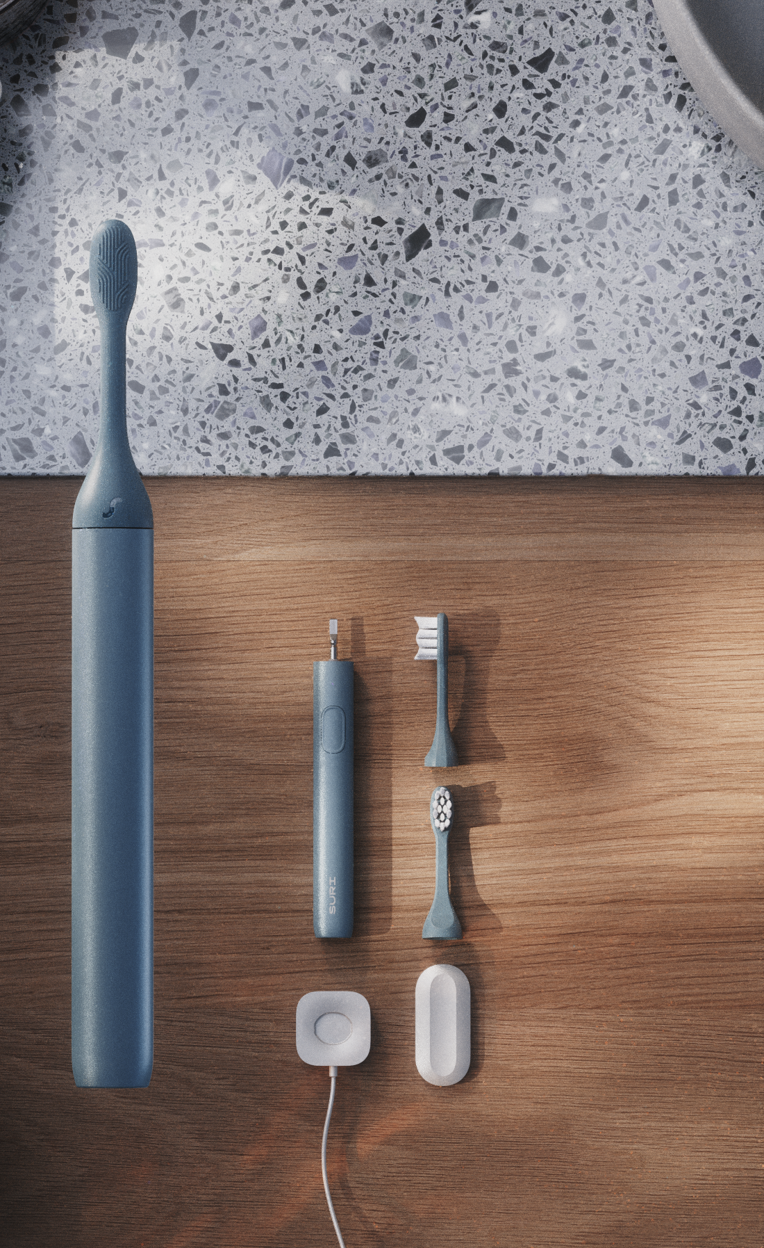 A sleek, blue electric toothbrush and its accessories laid out on a wooden surface, including a charging case and two replacement heads.