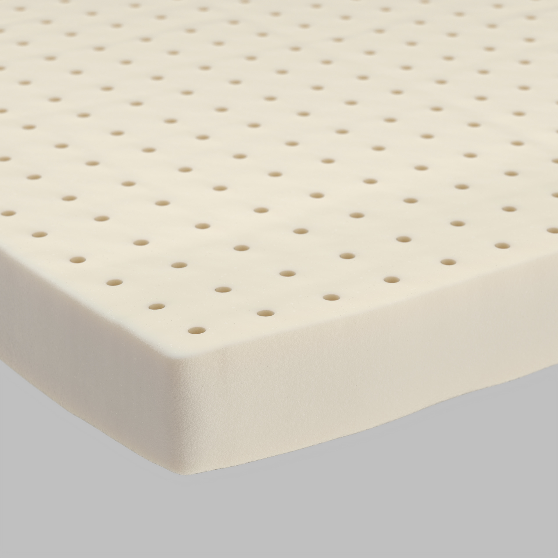 A close-up view of a natural latex mattress with evenly spaced holes, showing its breathable and supportive surface.