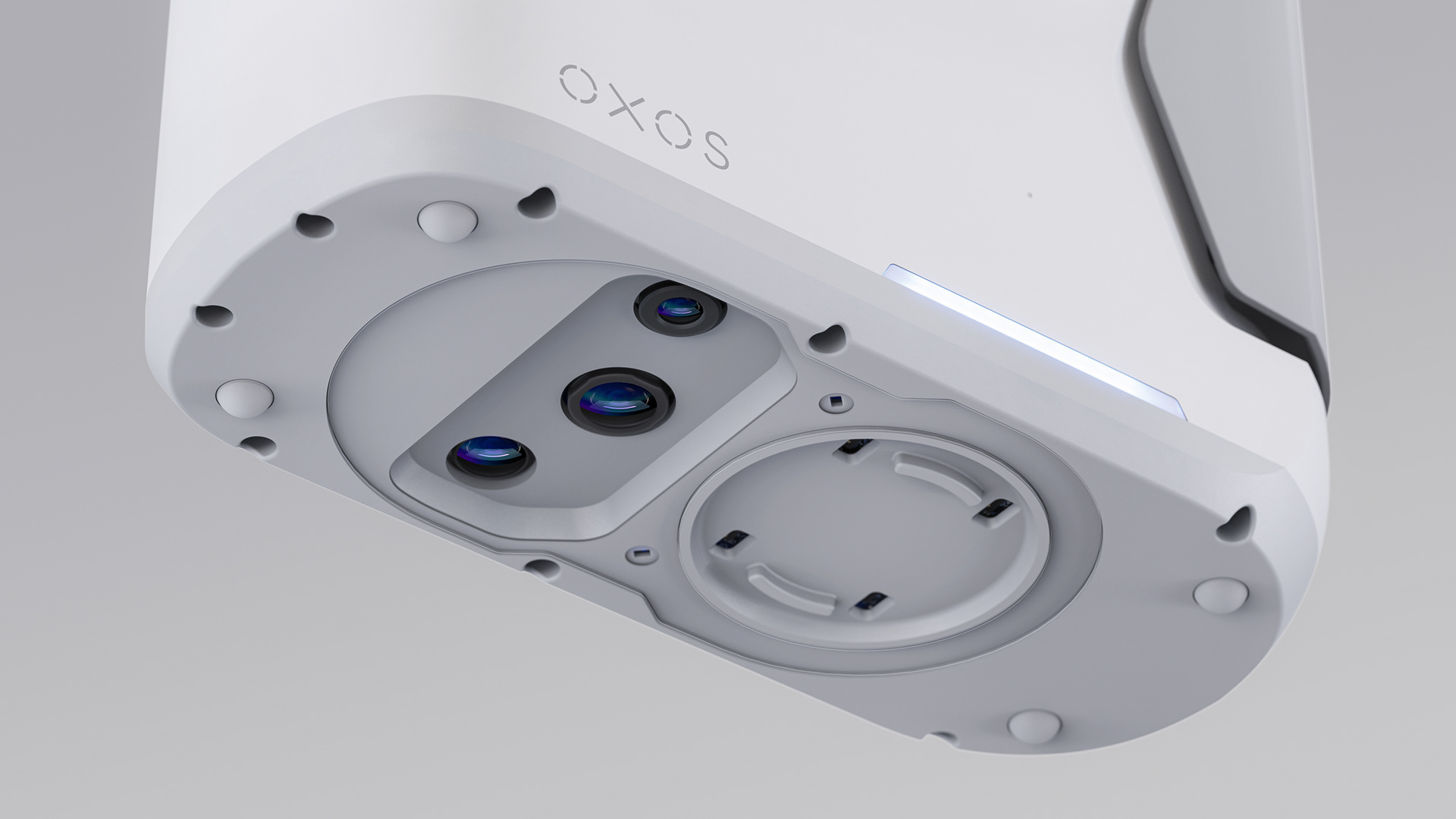 A close-up of a white device with "OXOS" text, featuring two lenses and a blue light indicator on its side.