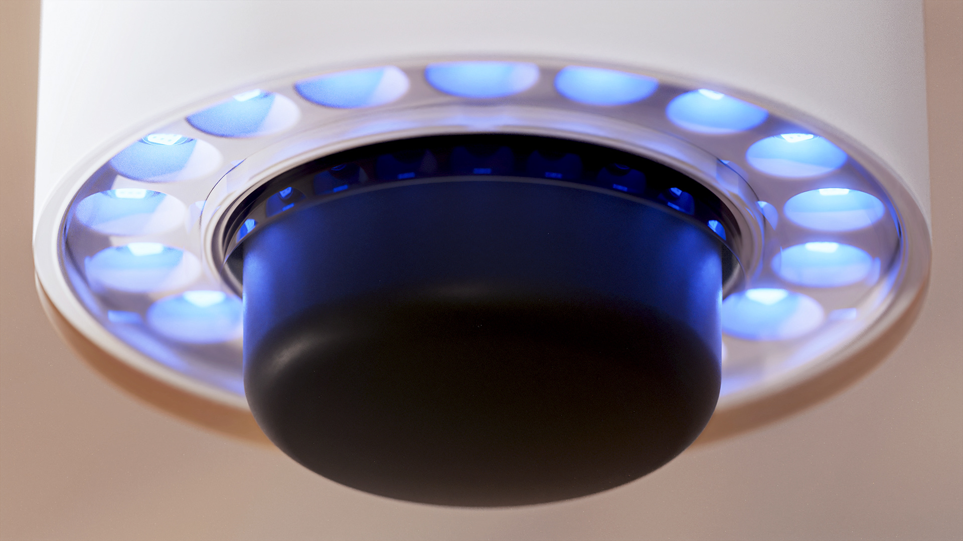A device with a circular blue light array and a black base.