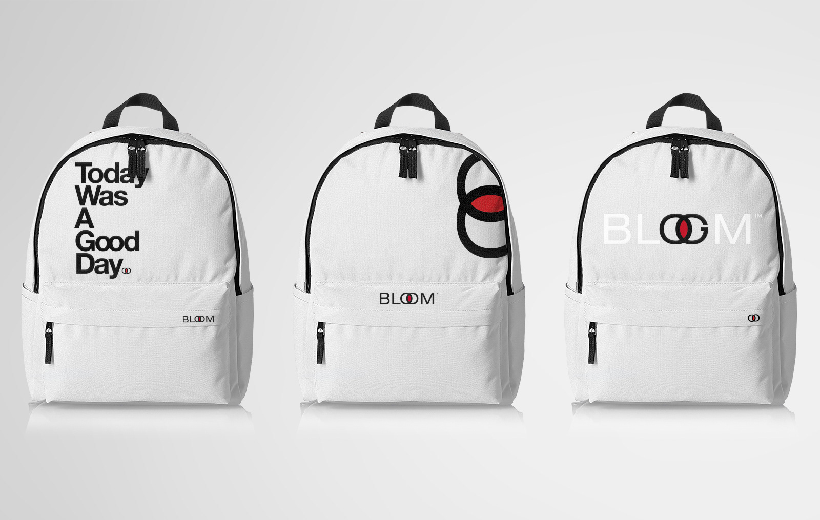 A white backpack with "Today Was A Good Day" printed on the front, featuring a playful face graphic and the "BLOOM" logo on the side.