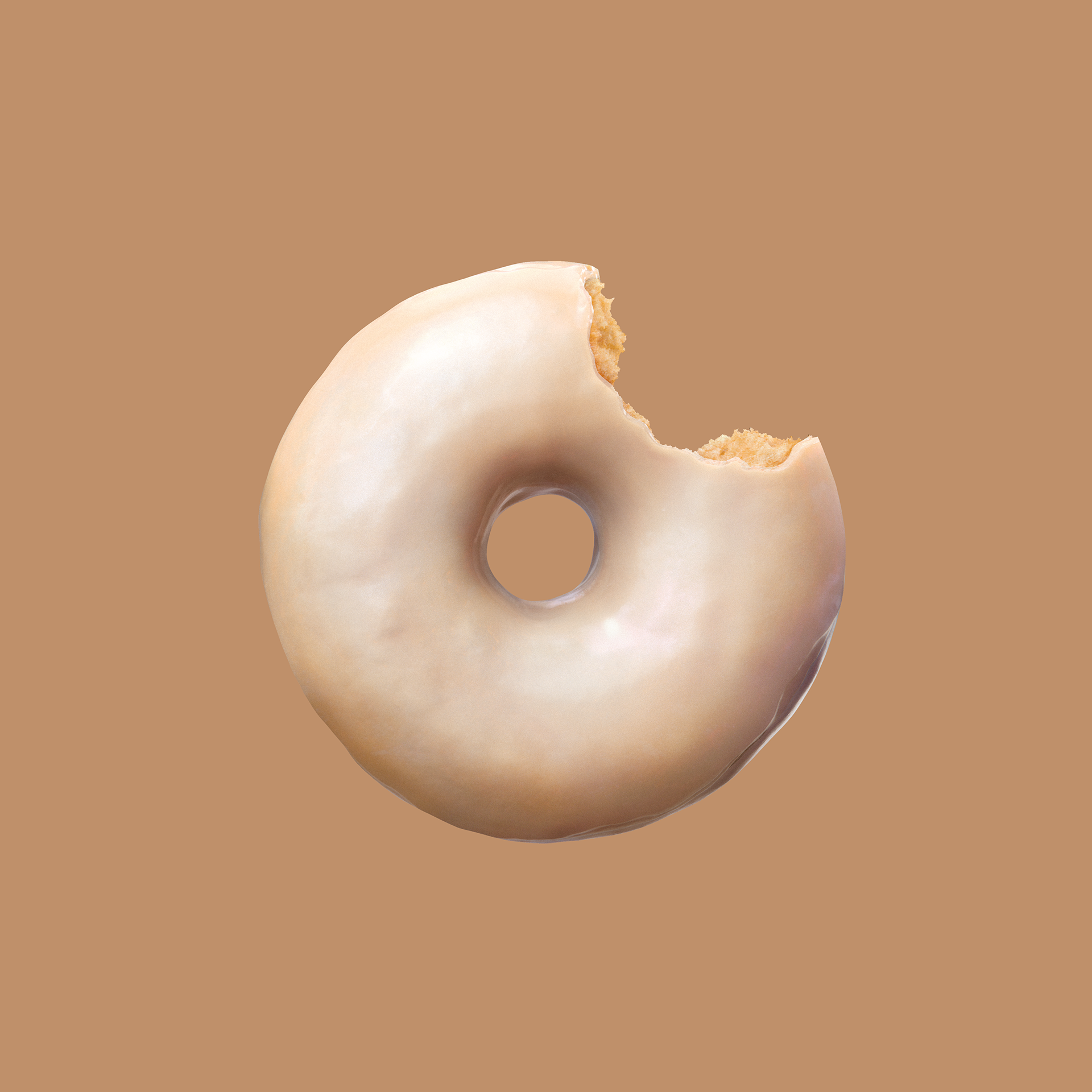 A glazed donut with a bite taken out of it, showing its soft texture and creamy glaze against a warm brown background.
