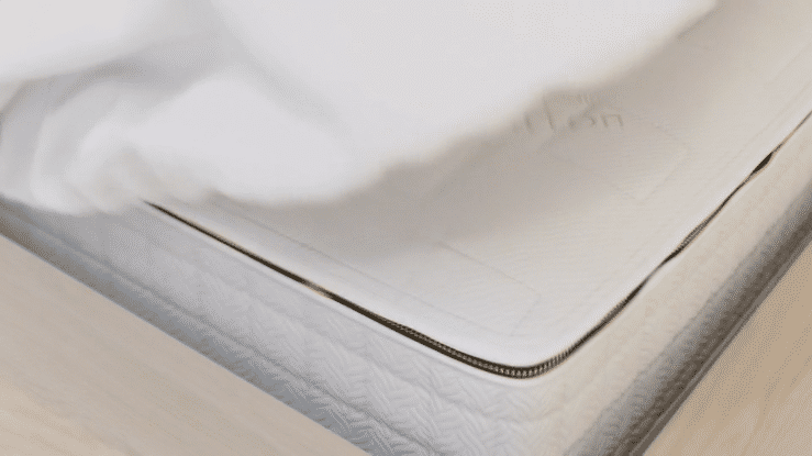 Animated sequence: A bed with a wooden headboard, featuring a white pillow and a gray blanket, with a light blue pillow partially visible on top.