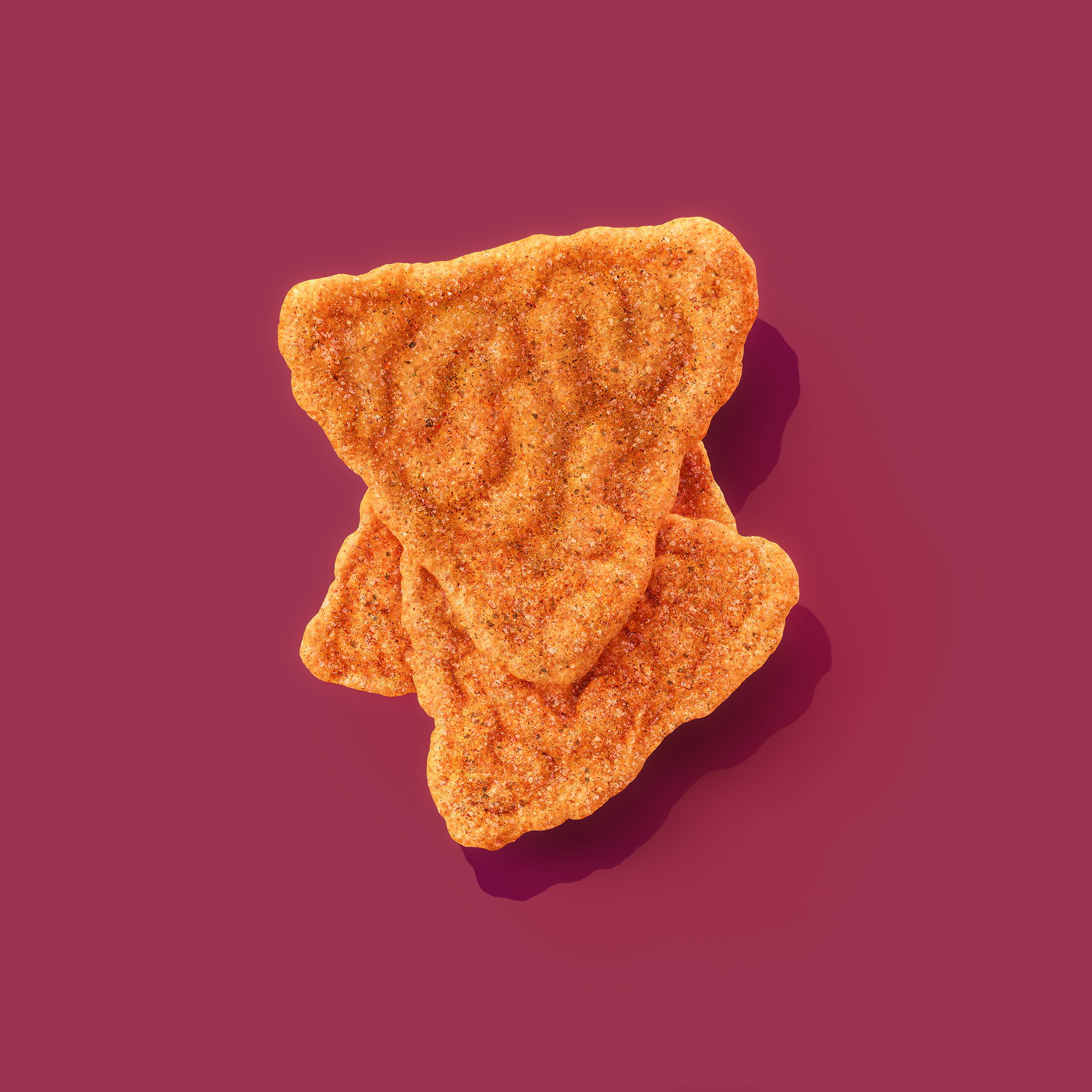 Two golden-brown, crinkled crackers stacked on a deep purple background.