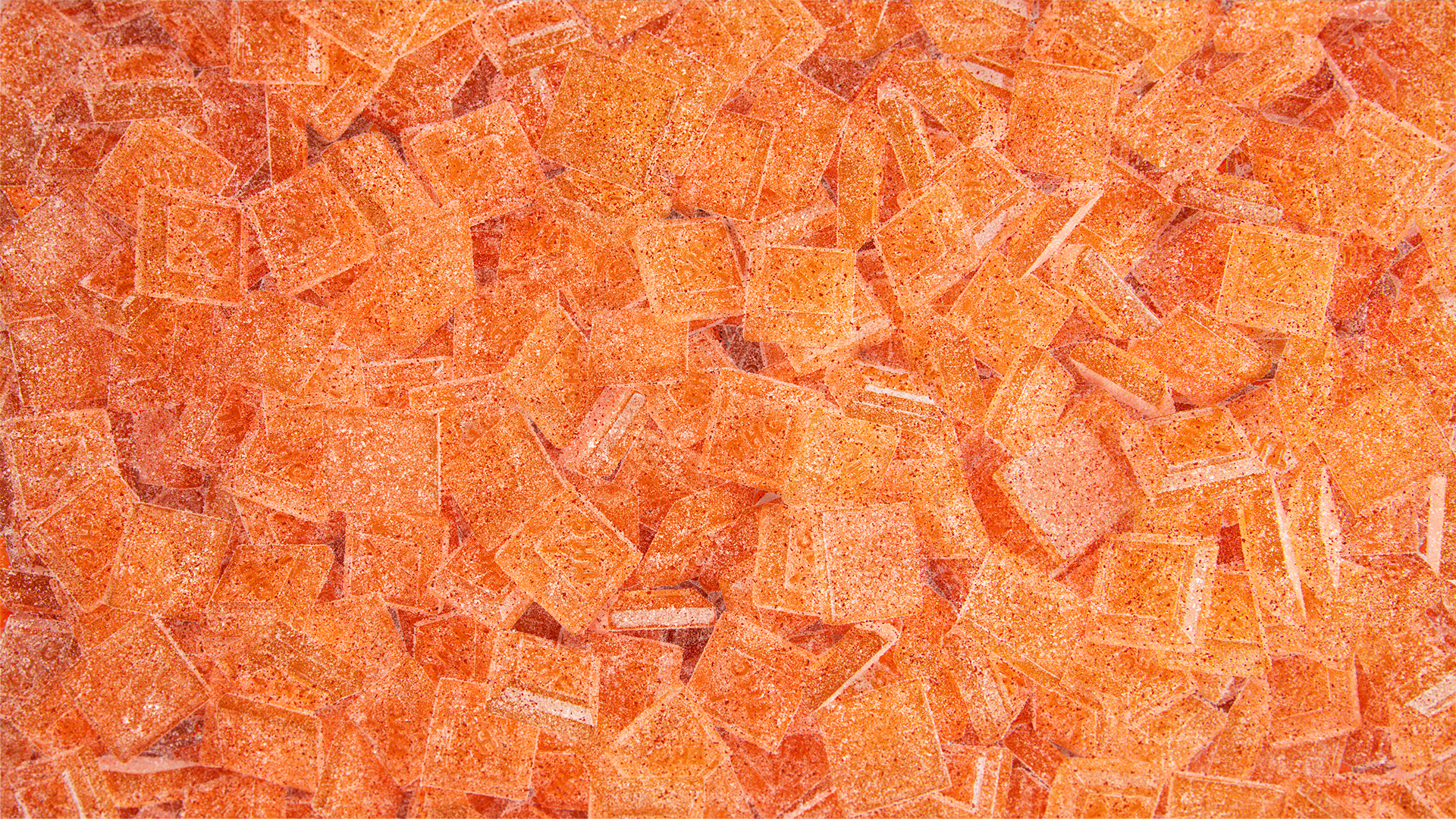 A close-up view of vibrant orange gummy candy pieces arranged in a random pattern.