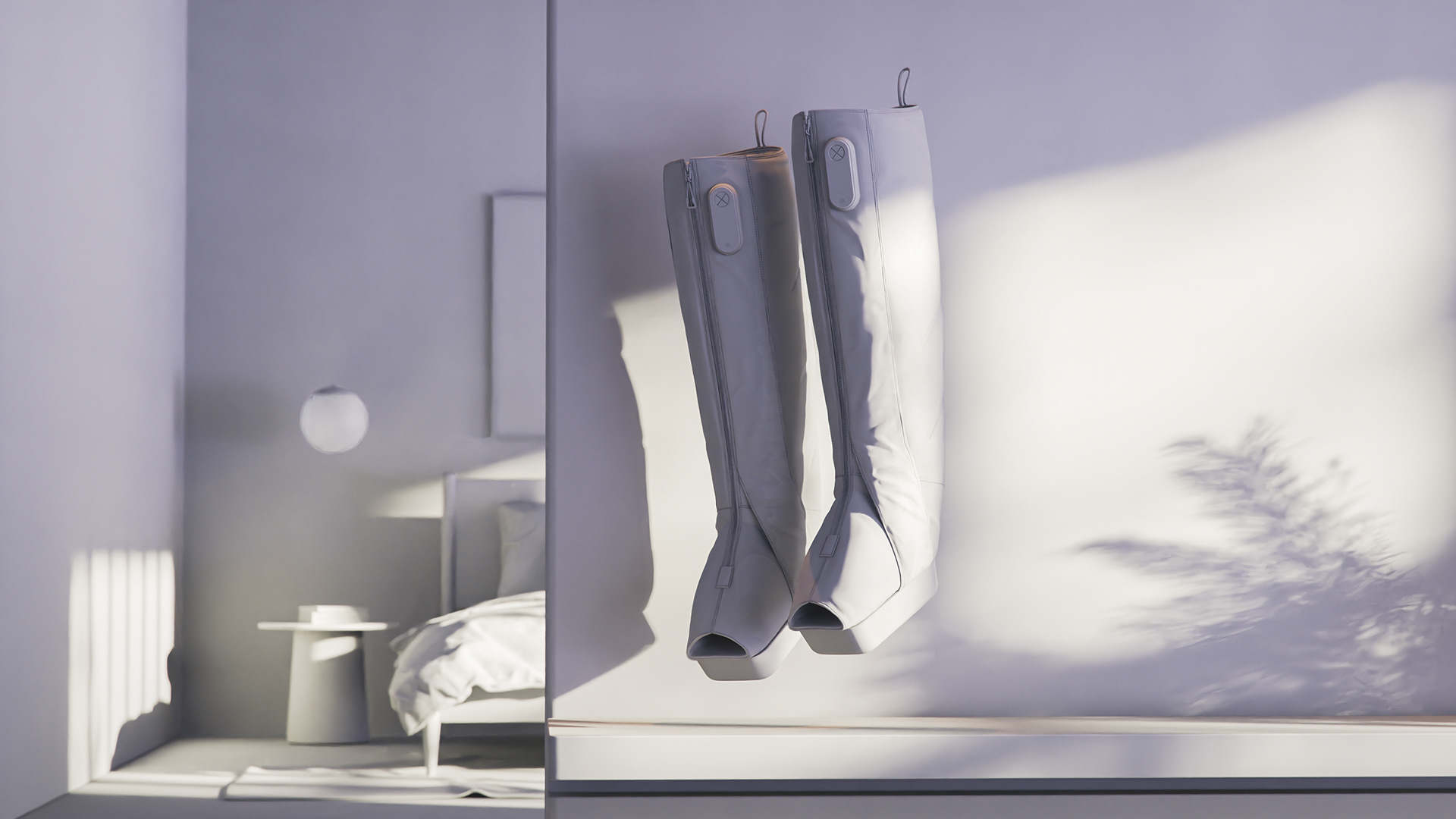 RECOVERYAIR JETBOOTS - THERABODY showcases a pair of gray jetboots hanging on hooks against a white wall, with sunlight casting shadows.