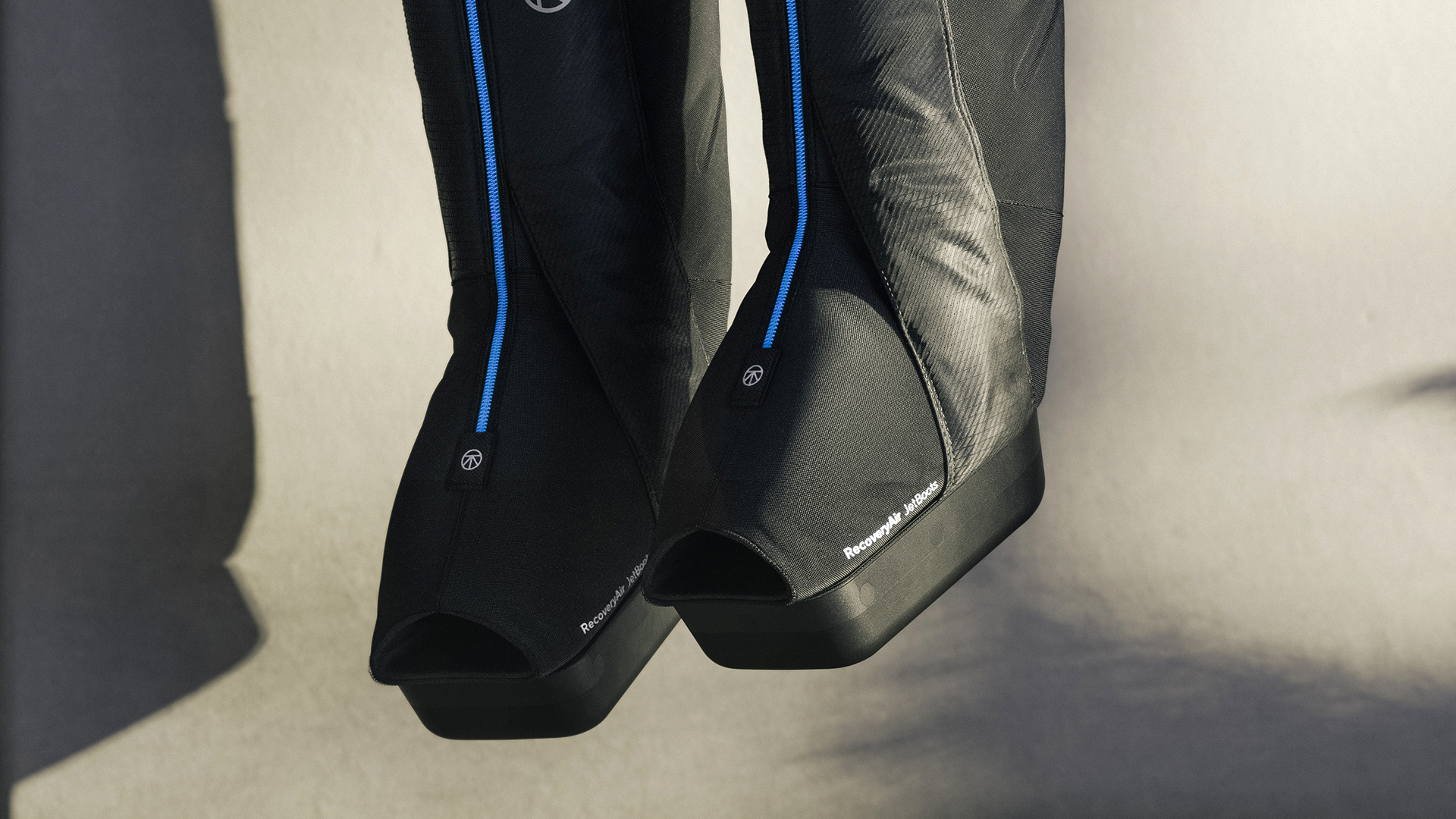 Close-up of black recoveryair jetboots with blue accents and "RecoveryAir" branding on the side.
