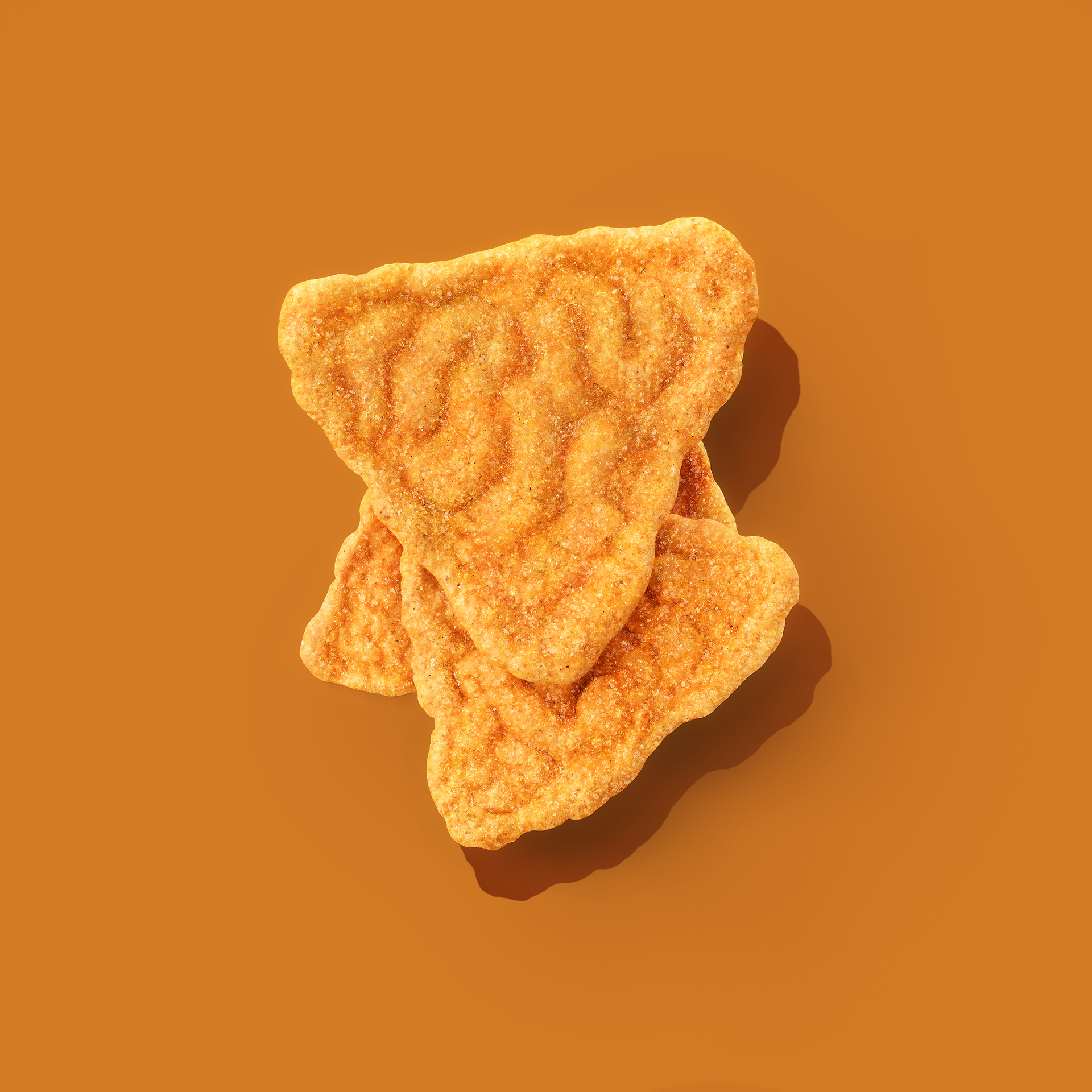 Three triangular crackers with a textured surface, stacked on top of each other against an orange background.