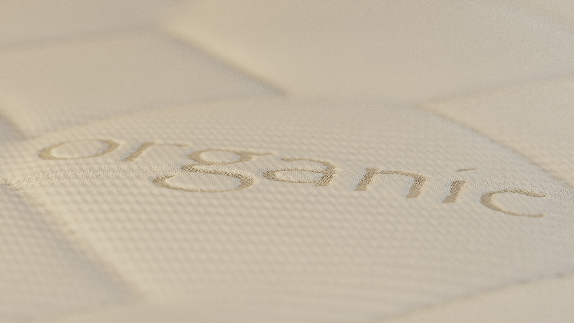 A close-up of a textured white surface with the word "organic" embroidered in thread.