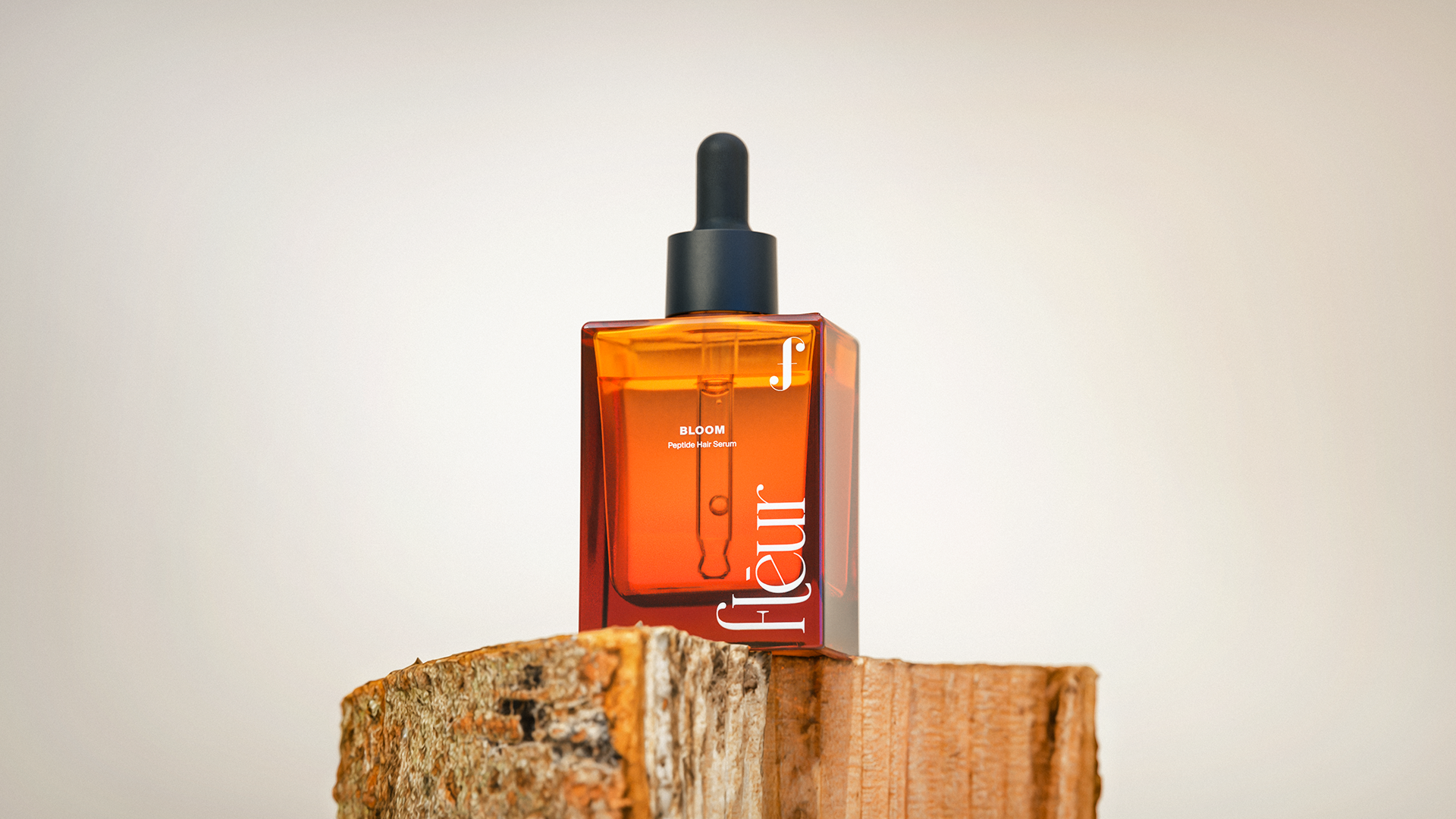 A sleek, amber-colored bottle of "BLOOM" peptides stands on a rustic wooden block, its label featuring elegant typography and a minimalist design.