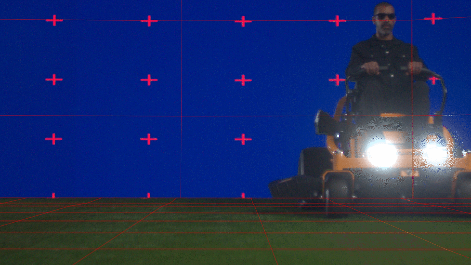 Animated sequence: A lawn mower with a red and black color scheme is shown from the side, positioned on a grassy field with a blue background featuring red plus signs.