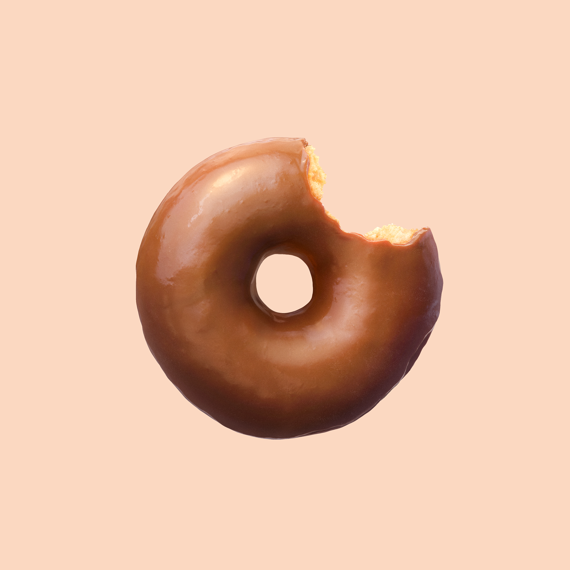 A chocolate-glazed donut with a bite taken out of it, set against a pastel background.