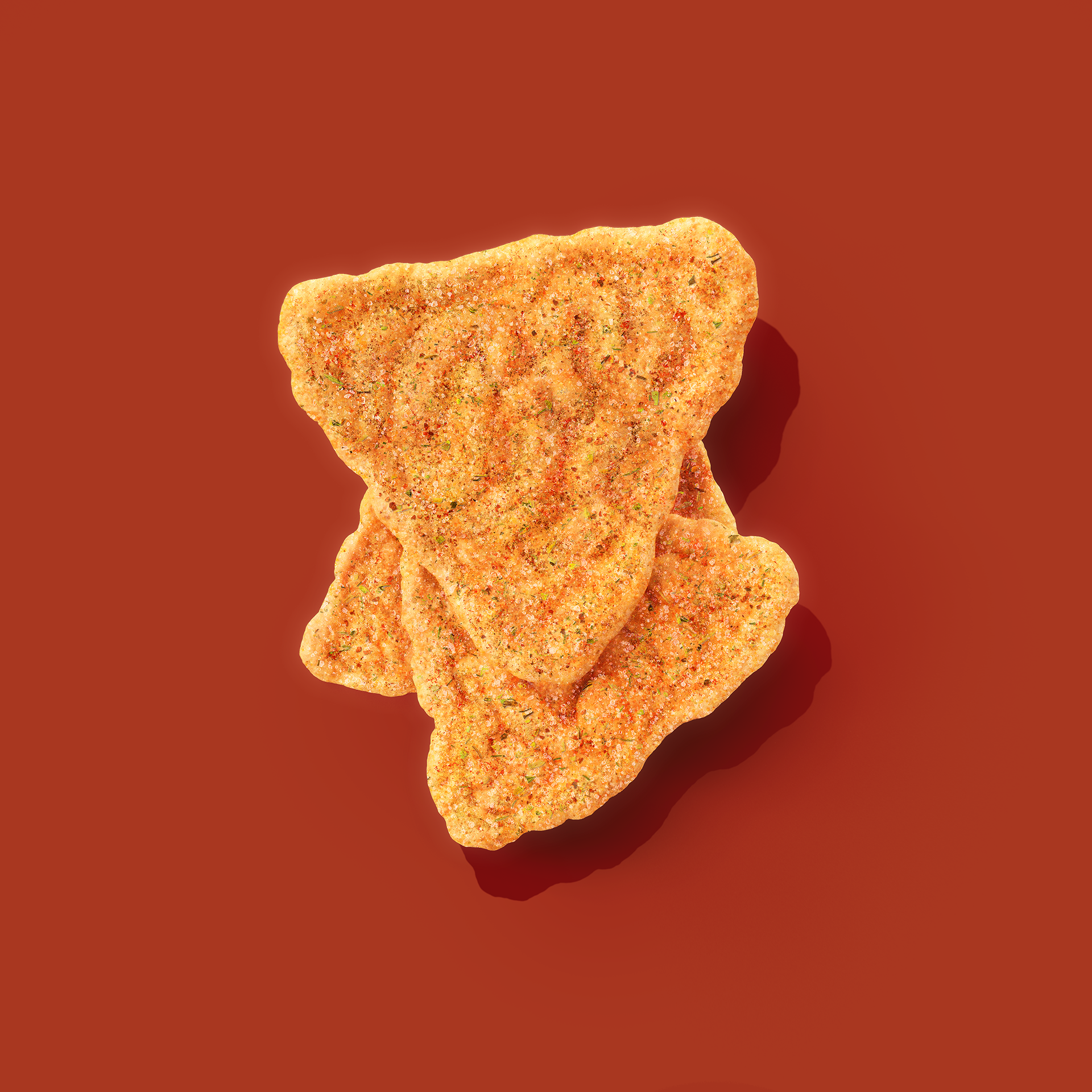 Crunchy, seasoned crackers with a heart shape, stacked on a red background.