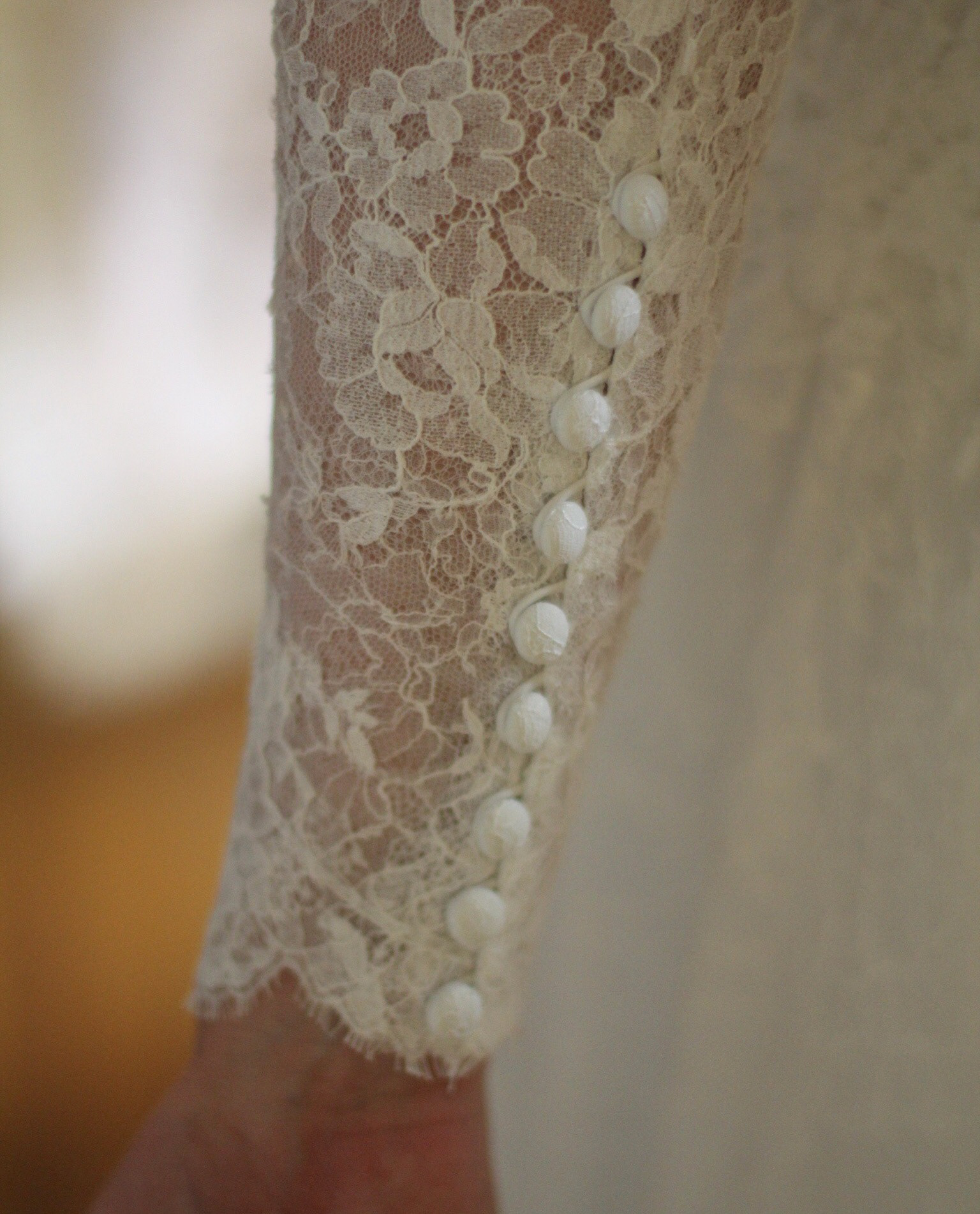 A close-up of the buttons on the sleeve of Caroline's gown.