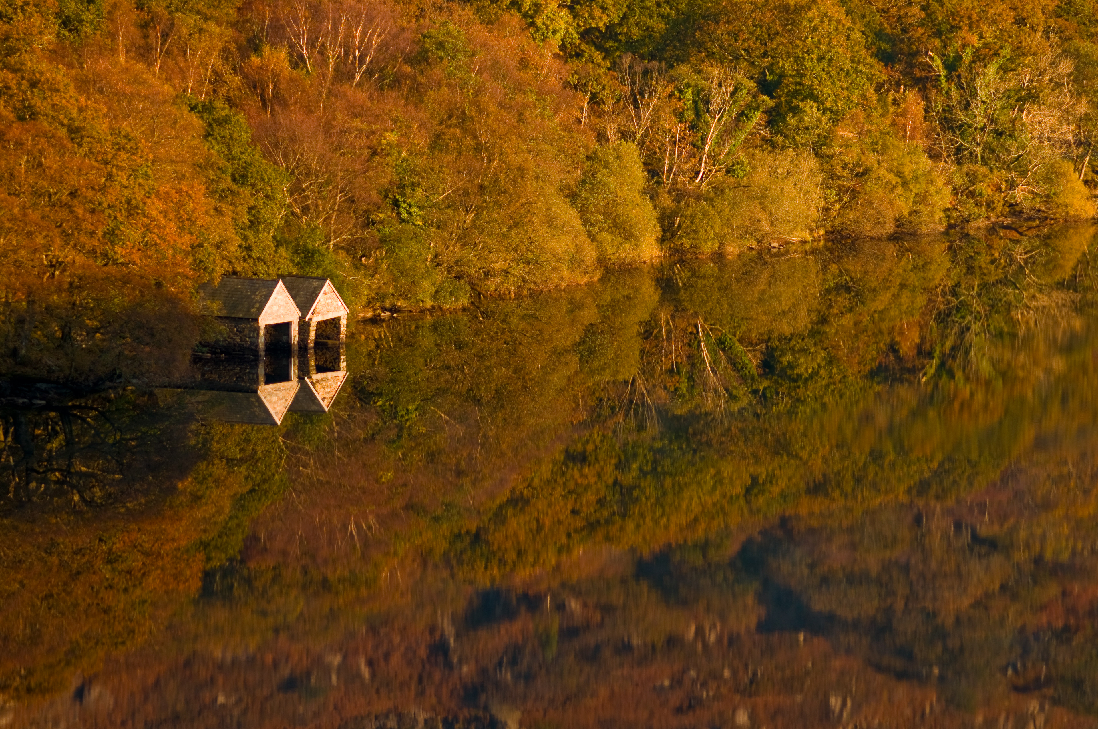Autumn reflection of boat houses on Llyn Dinas, Snowdonia National Park.