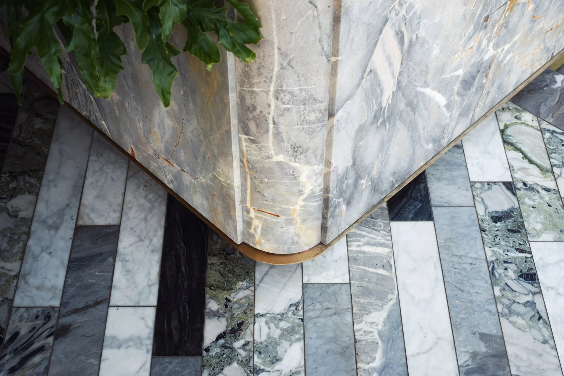 Brass base projects from stone wall, adding warmth and definition.