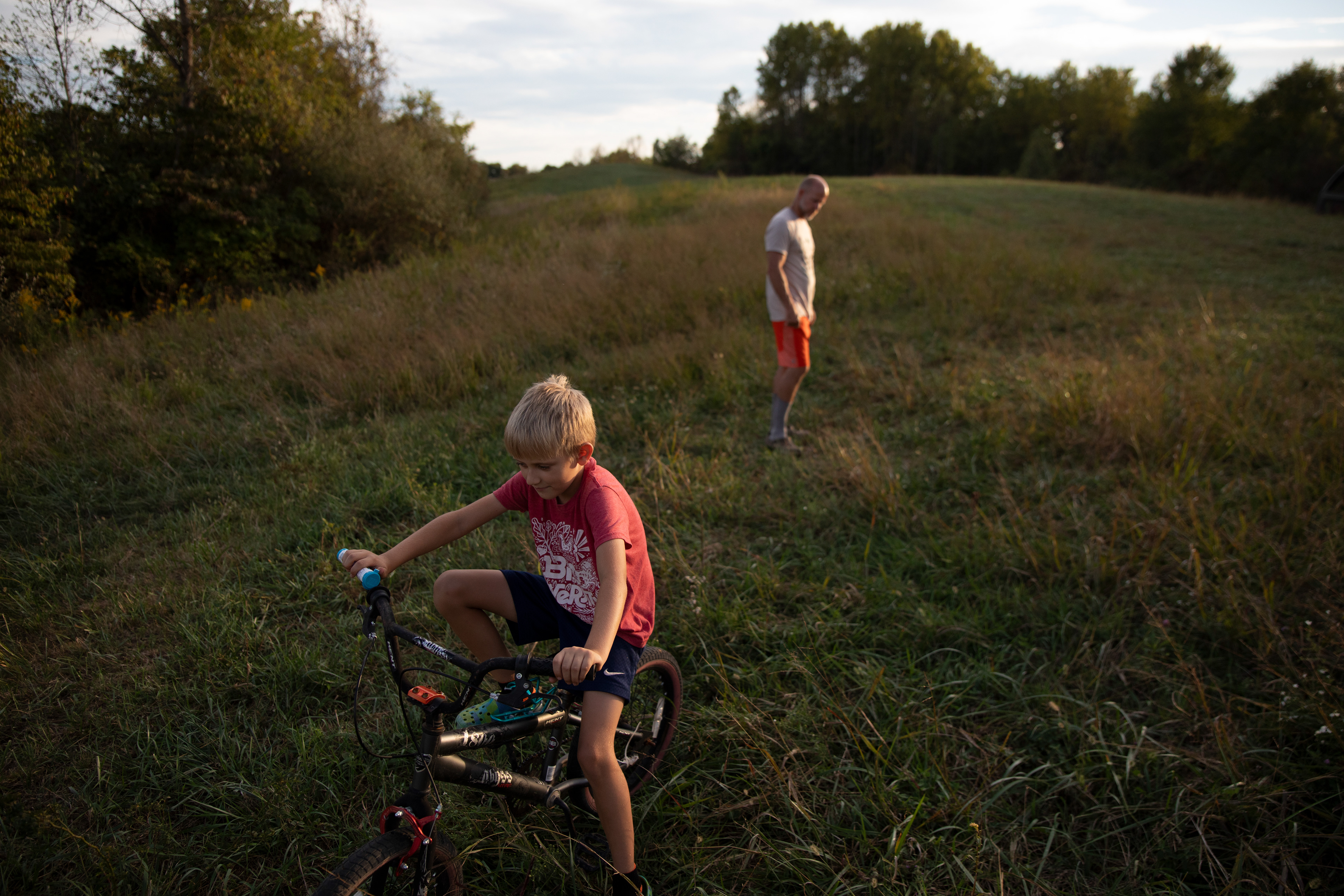 Will and Eric Gibson stand in a patch of grass that they are attempting to reintroduce after it was trampled and damaged for decades by tractors at Sugar Butte Farms in Lowell, Ohio, Sept. 23, 2024. 