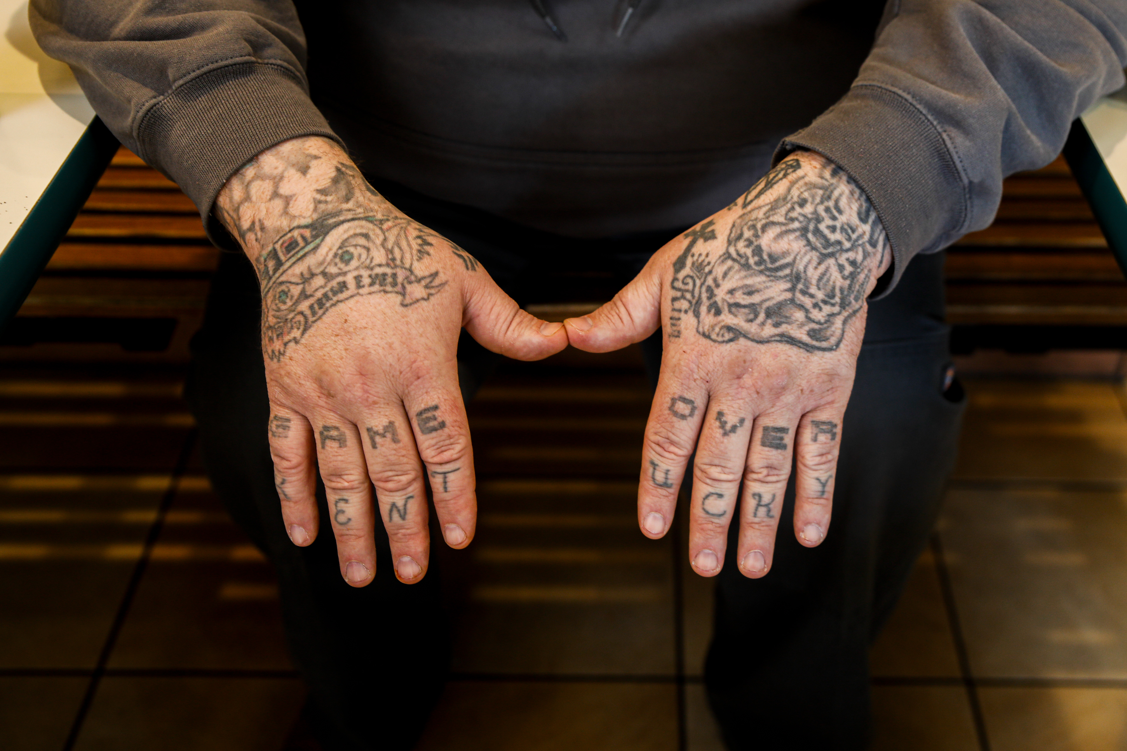 Anthony Holland shows his hand tattoos at Larry's Dawg House on W. Union St. in Athens, Ohio, February 20, 2024. Across eight fingers Holland has the words "GAME OVER" and "KENTUCKY", the latter representing his home state. Holland has 35+ tattoos, and when asked if he regrets any he explained, "Yeah, a few. But not really. They all represent memories, they all got a story."