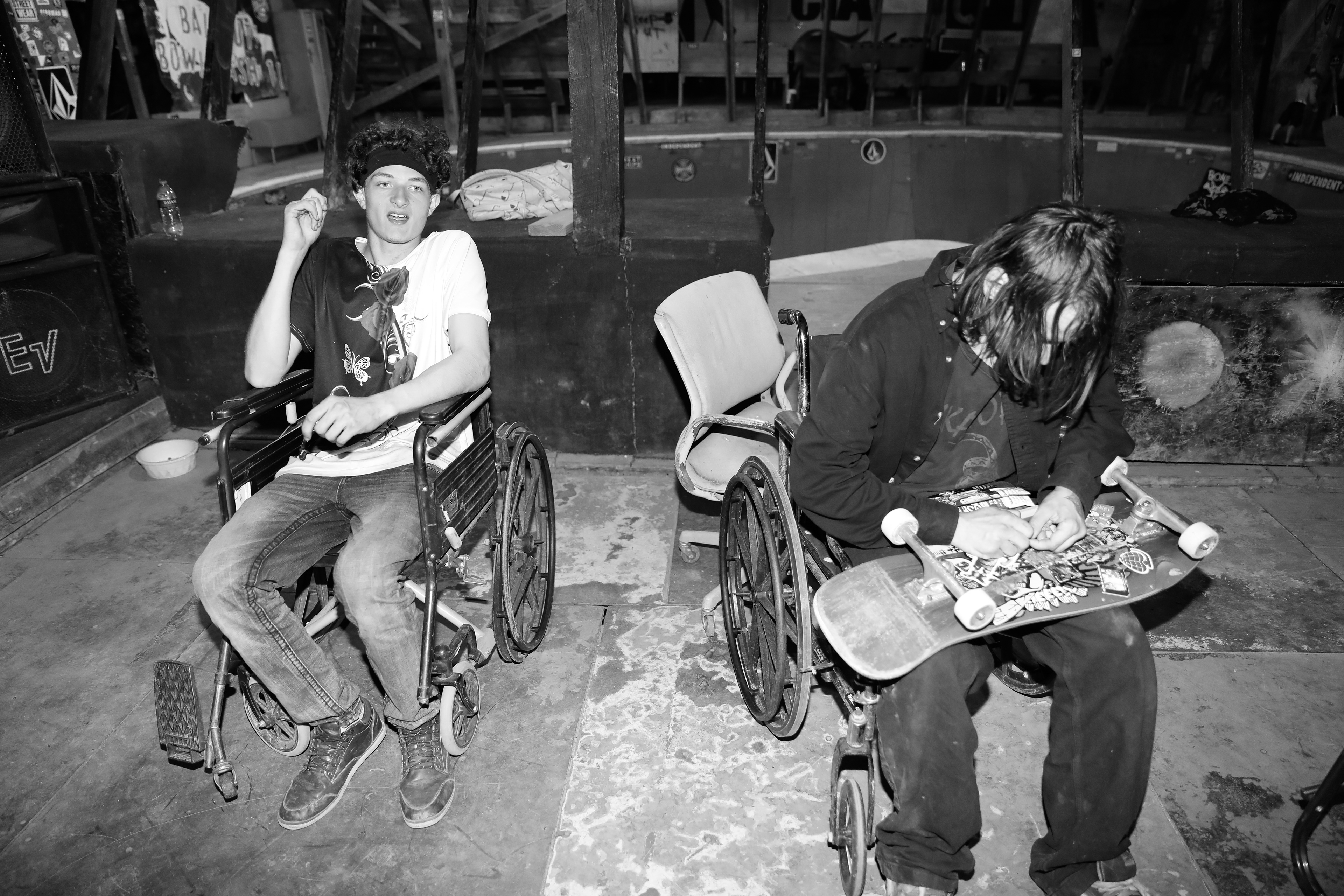 Two men smoke and sit on wheelchairs inside the one of the indoor sections of Skatopia during the three day Work Party event at Skatopia in Rutland, Ohio, March 30, 2024.