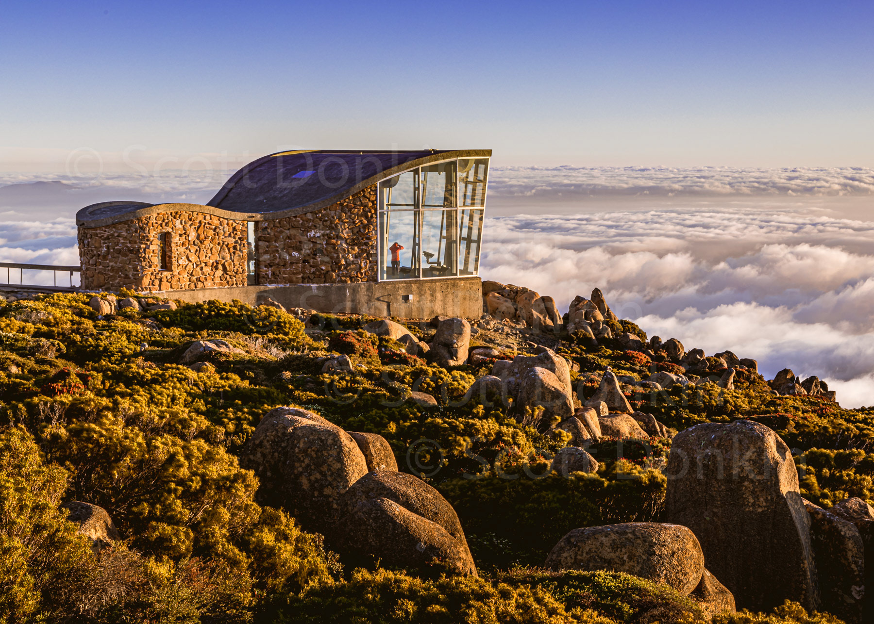 MOUNT WELLINGTON, HOBART, TAS, AUSTRALIA - 19 December 2019: A 'cloud inversion' obscures the view for a lone spectator on what would otherwise be a crisp morning panormama of Hobart, 1271 metres below.
