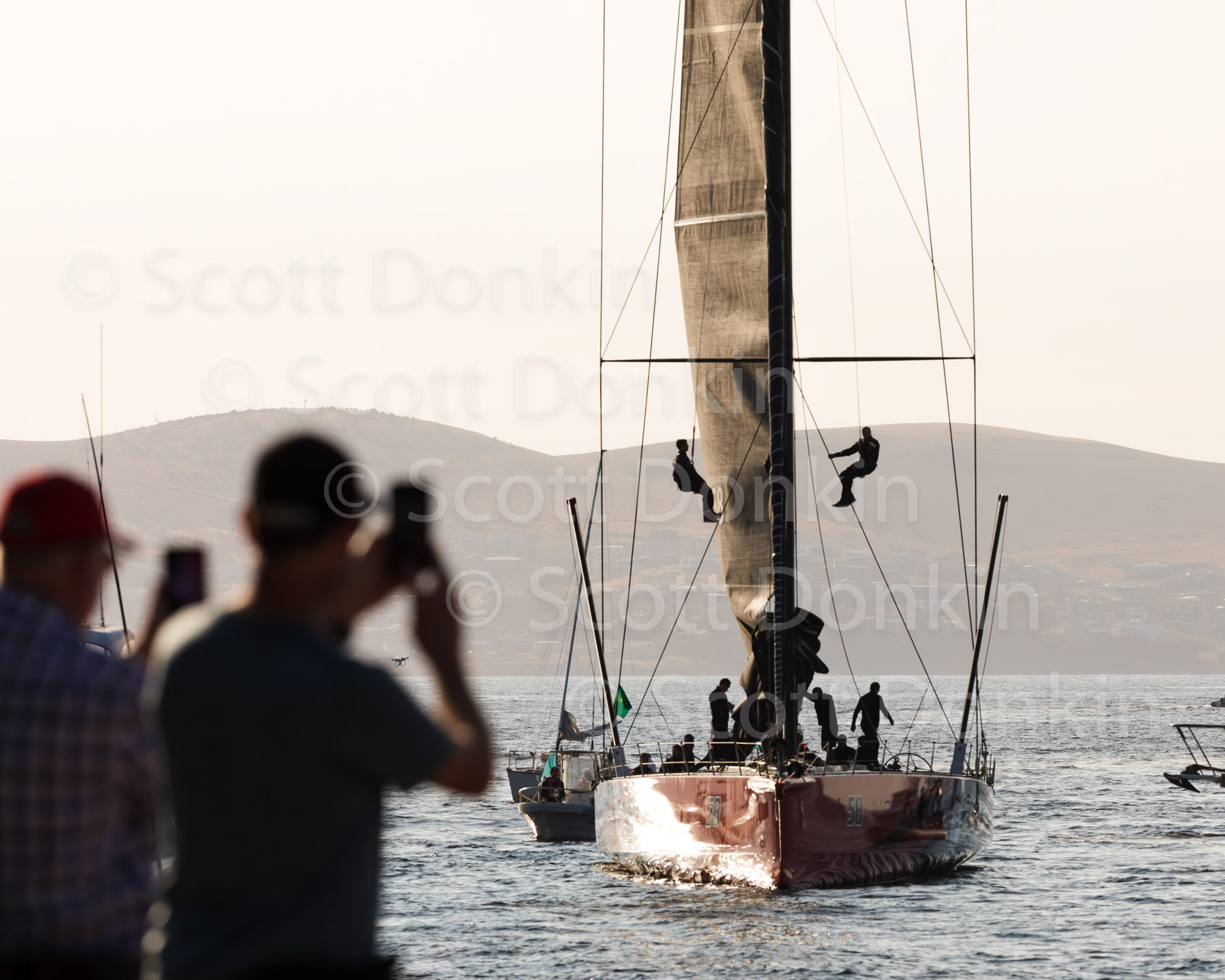 HOBART, TAS, AUSTRALIA - 28 December 2019: Spectators on the docks at Hobart welcome the arrival of Commanche, Line Honours winner of the 2019 Rolex Sydney Hobart Yacht Race as crew lower the mainsail.