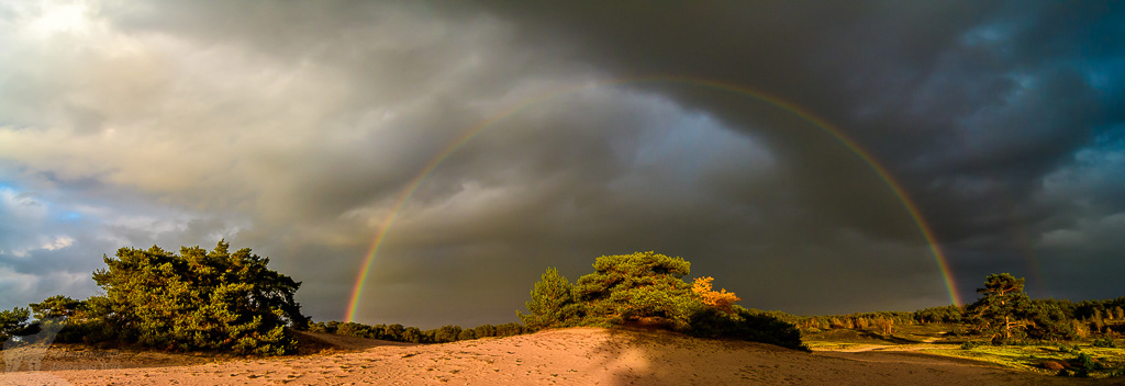 Regenboog boven zandverstuiving