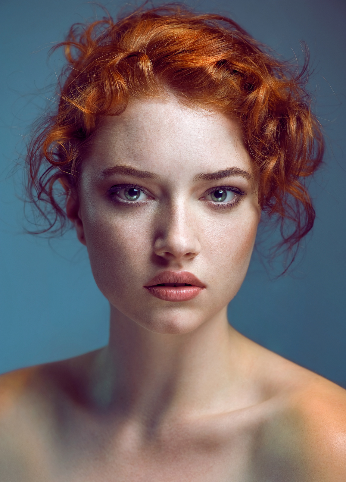 Editorial beauty portrait of red-haired model with natural makeup against blue backdrop – Joanna Kustra fashion photography