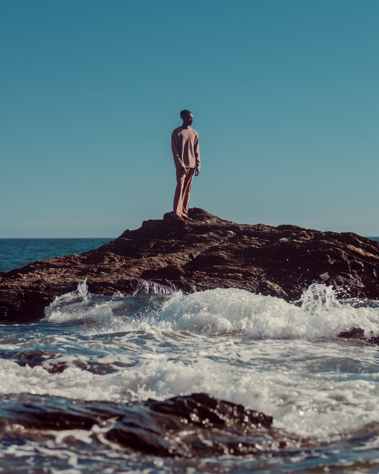 Dramatic fashion editorial of male model standing on coastal rocks – Joanna Kustra outdoor photography