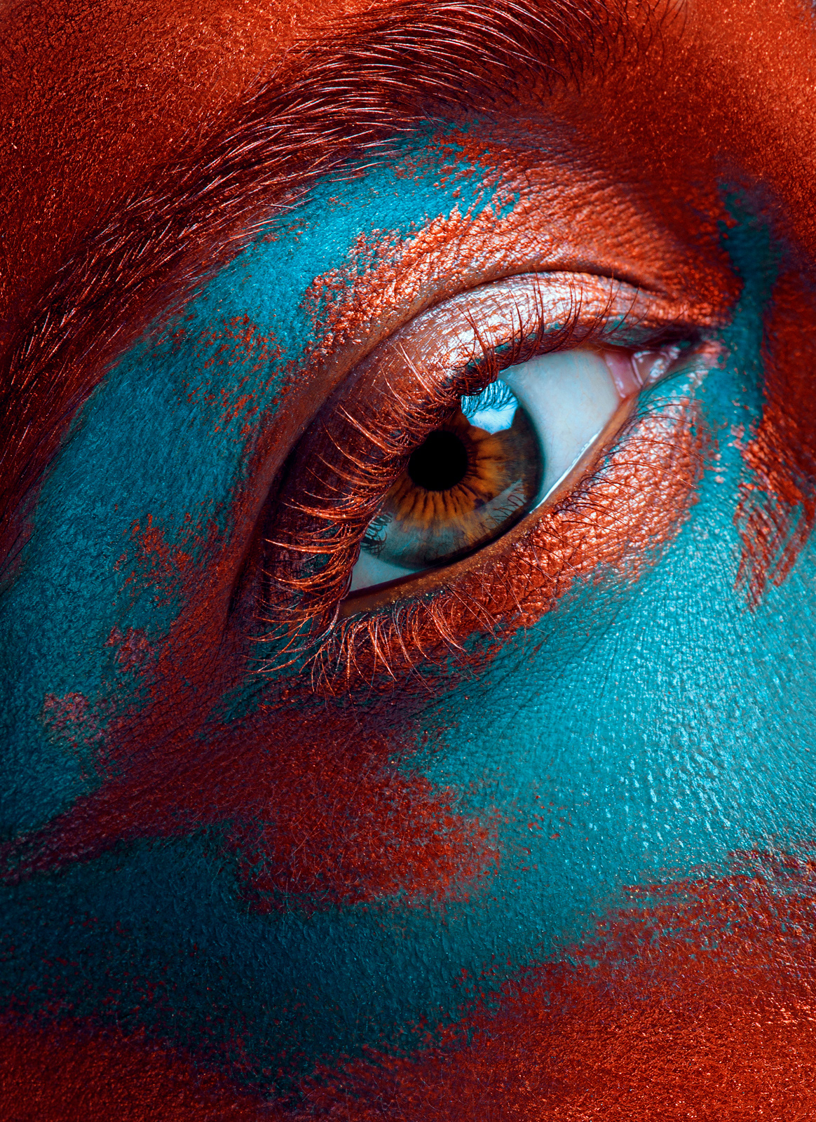 Creative beauty close-up with blue and red face paint around the eye – Joanna Kustra artistic beauty photography