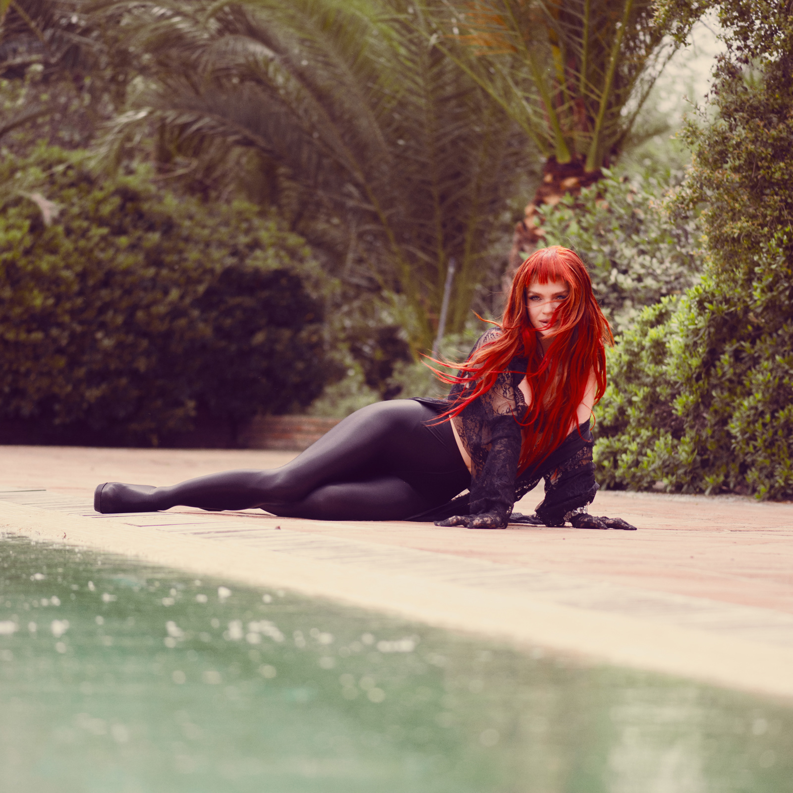 Outdoor fashion portrait of red-haired model Margaret in black gown with lace train by the pool – Joanna Kustra luxury editorial photography