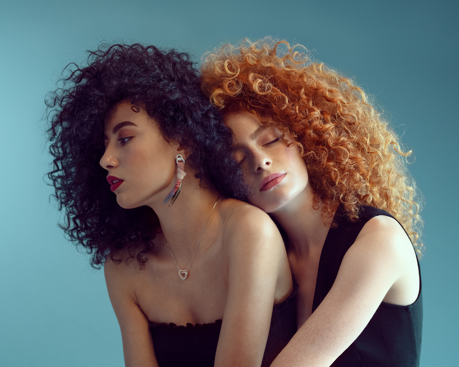 Editorial portrait of two women with voluminous curls in close embrace – Joanna Kustra beauty and fashion photography